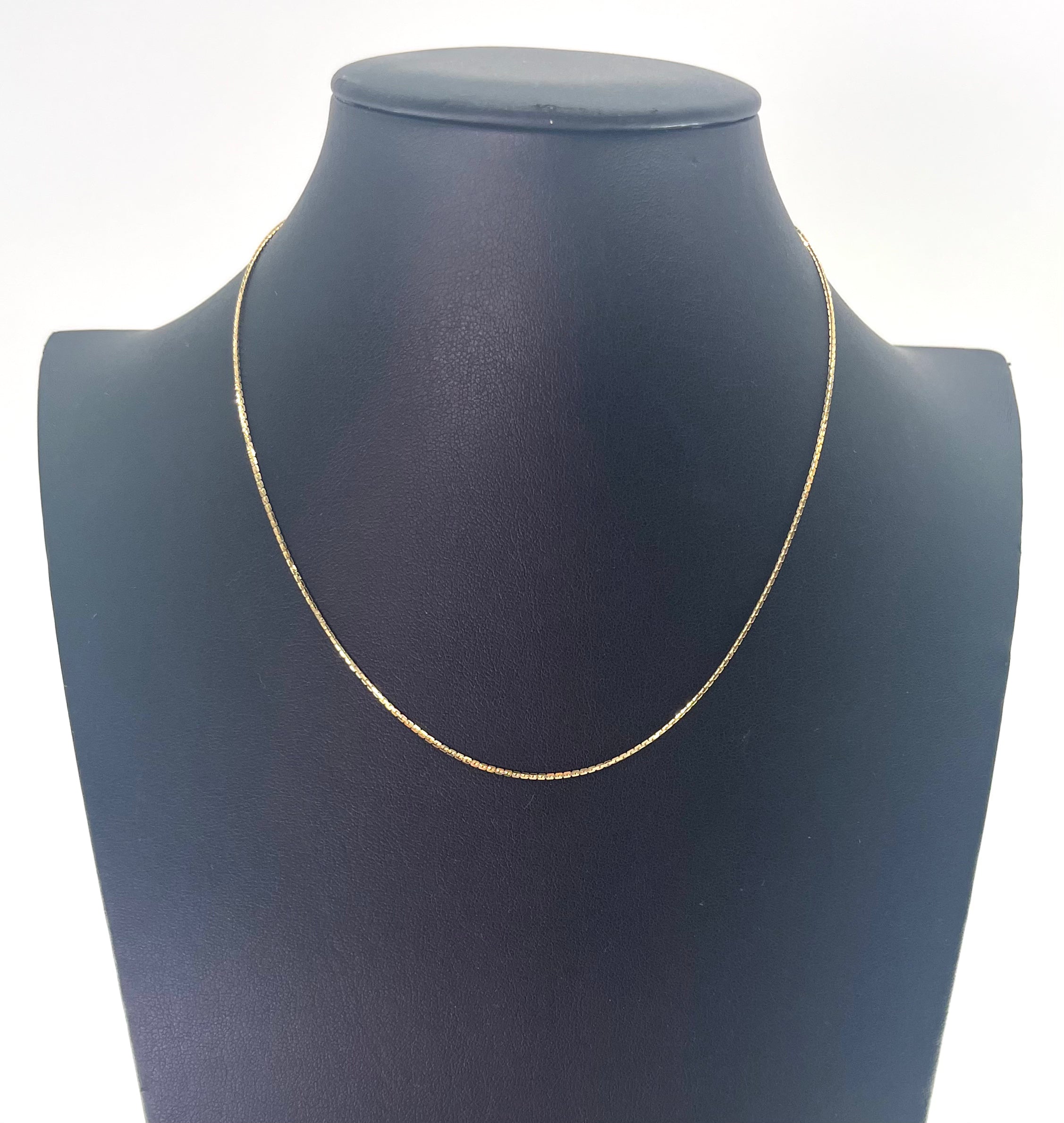 A CB STORES gold box chain necklace is displayed on a black jewellery bust against a plain white background.