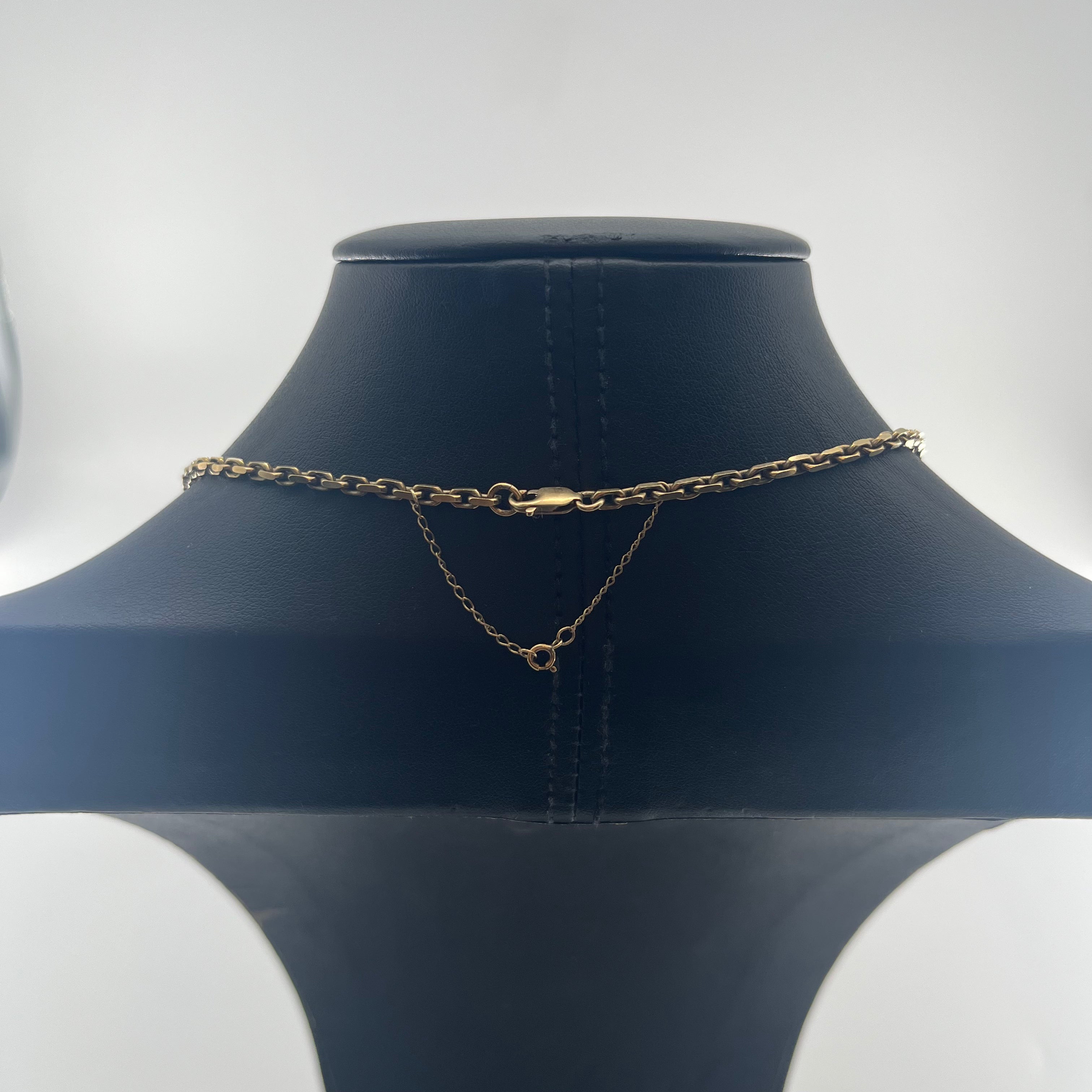 CB Stores yellow gold anchor chain necklace displayed on a black stand with a small V-shaped secondary chain near the clasp.