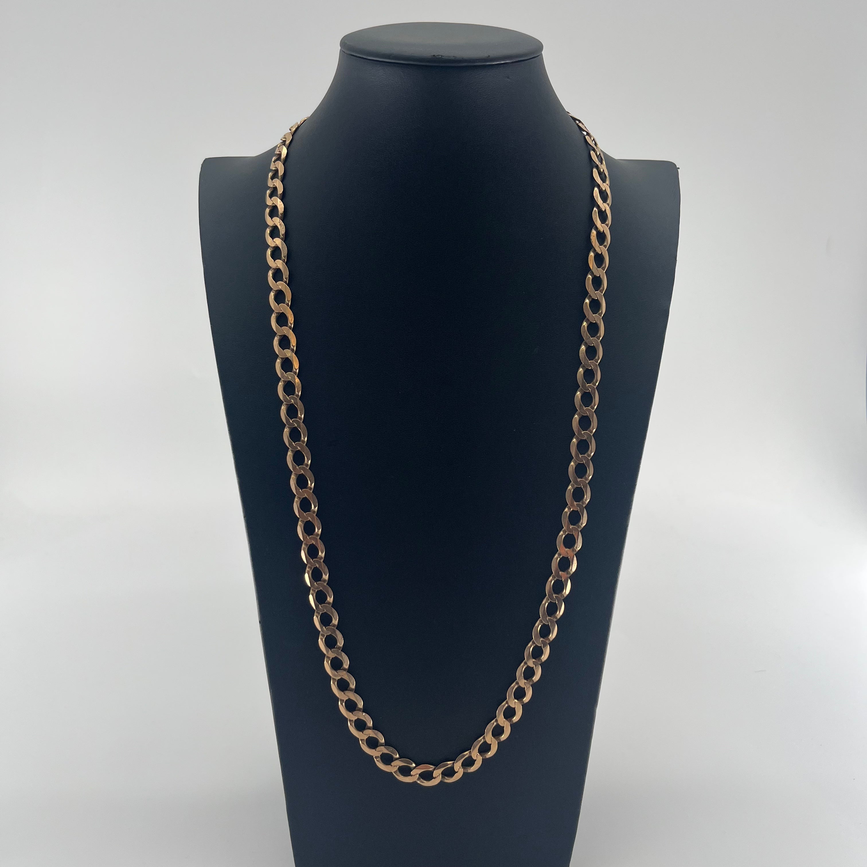 CB STORES yellow gold Figaro chain with oval links displayed on a black stand, set against a plain white background.