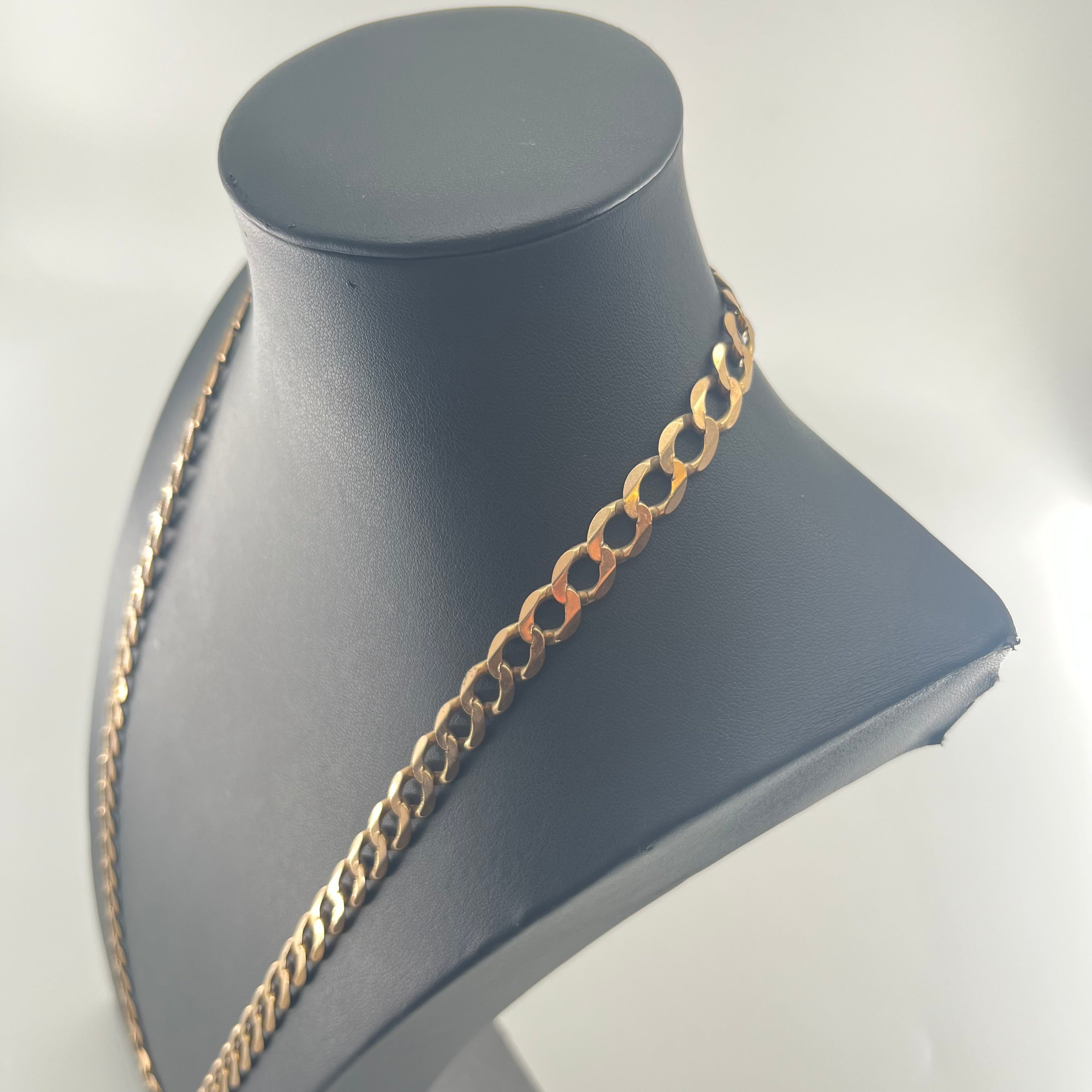 CB STORES yellow gold Figaro chain with flat interlocking links displayed on a black mannequin bust against a light background.