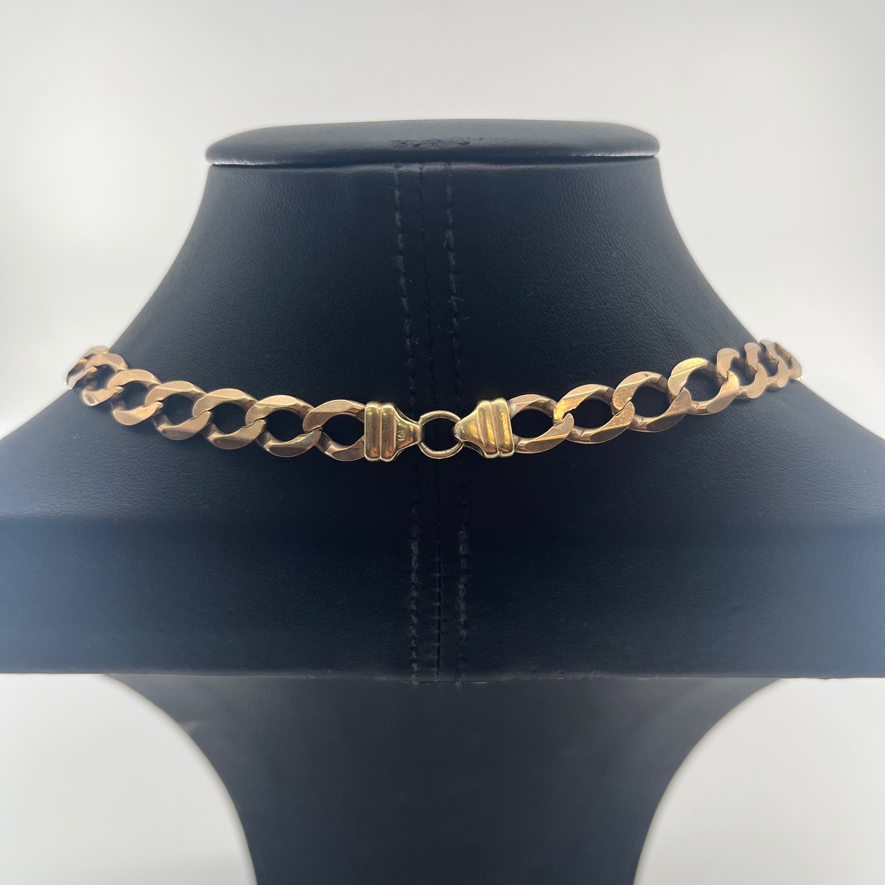 CB Stores yellow gold Figaro chain necklace with large interlocking links and centre clasp, shown on a black jewellery stand.