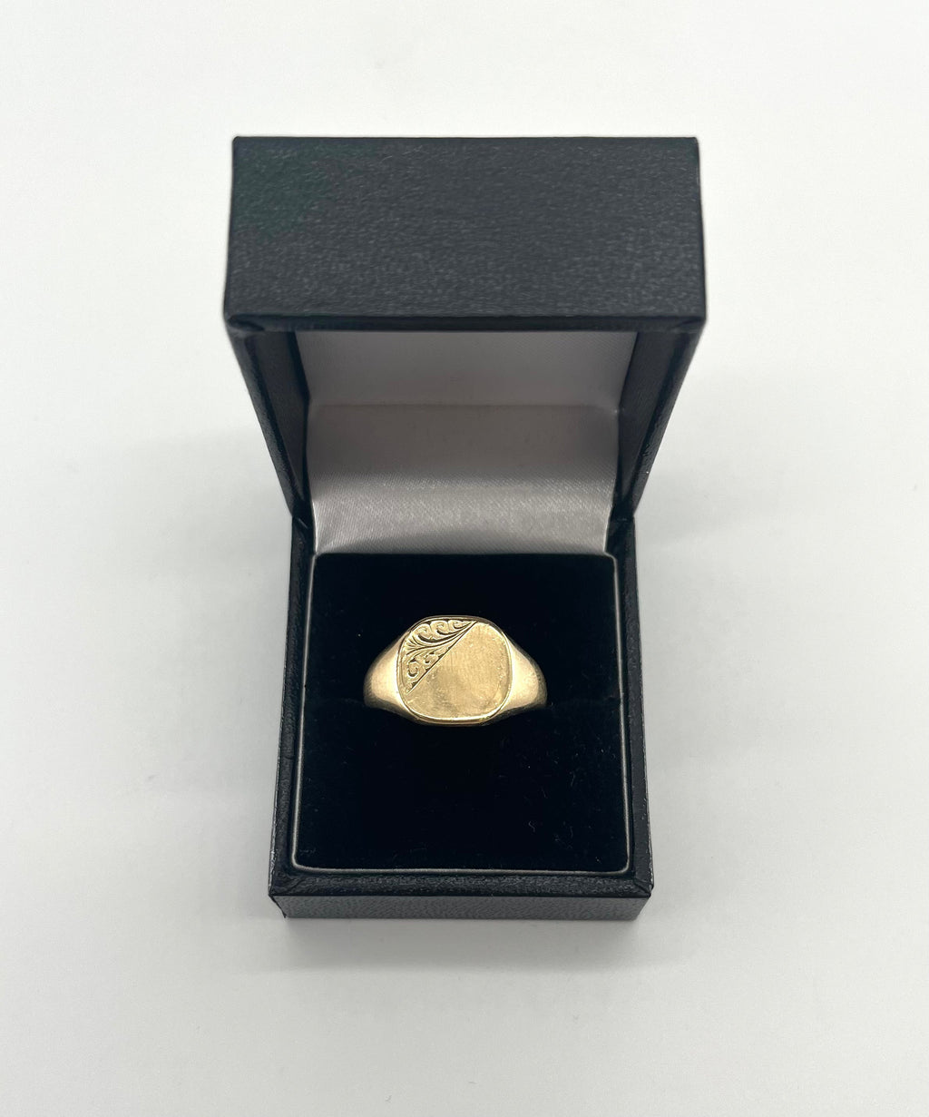 CB STORES 9ct square signet ring, partly engraved, displayed upright in a black ring box with white lining on a plain background.
