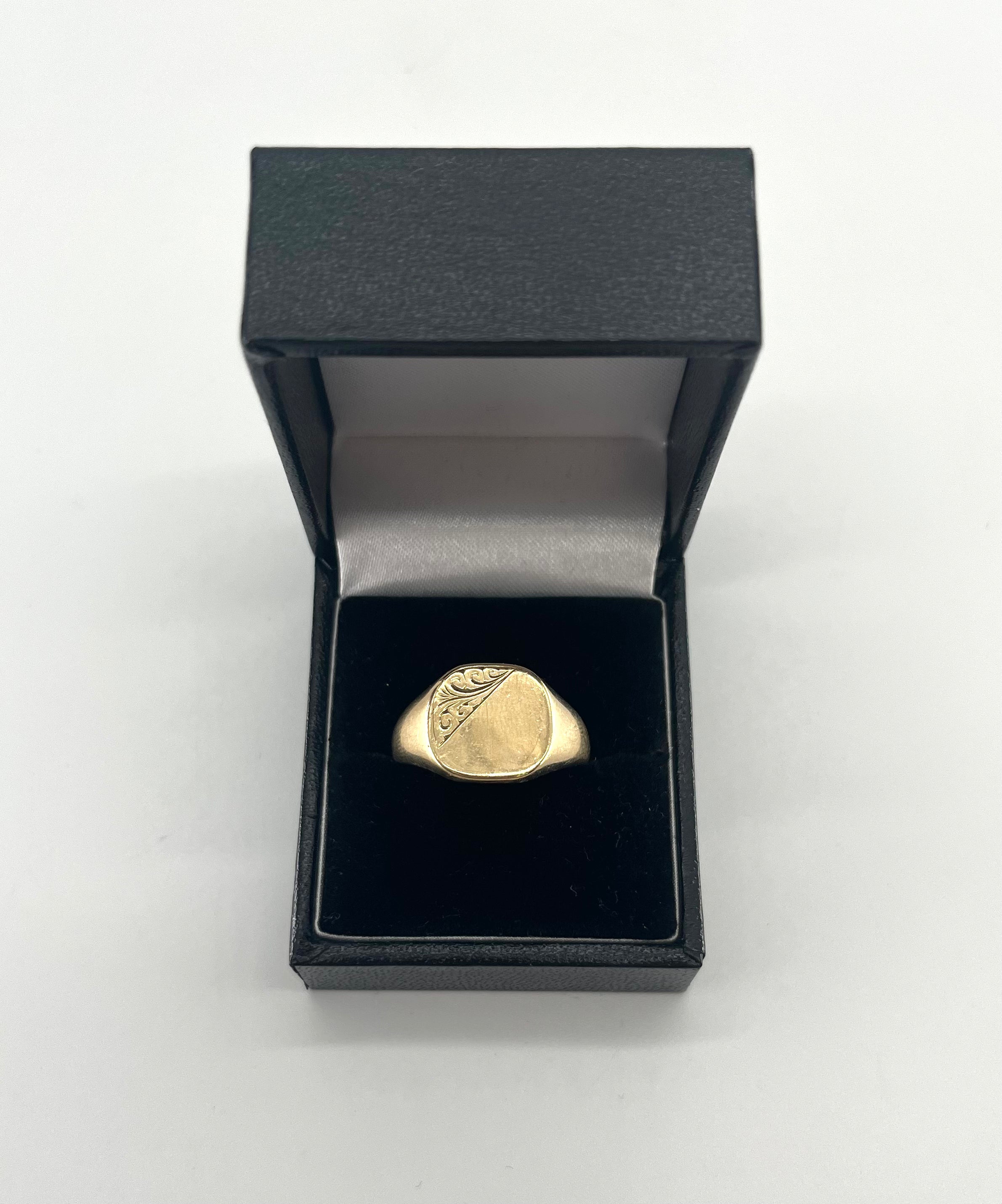 CB STORES 9ct square signet ring, partly engraved, displayed upright in a black ring box with white lining on a plain background.