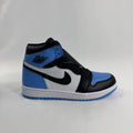 A Nike high-top trainer in black, white and light blue with a black Swoosh and Air Jordan logo, shown on a white surface.