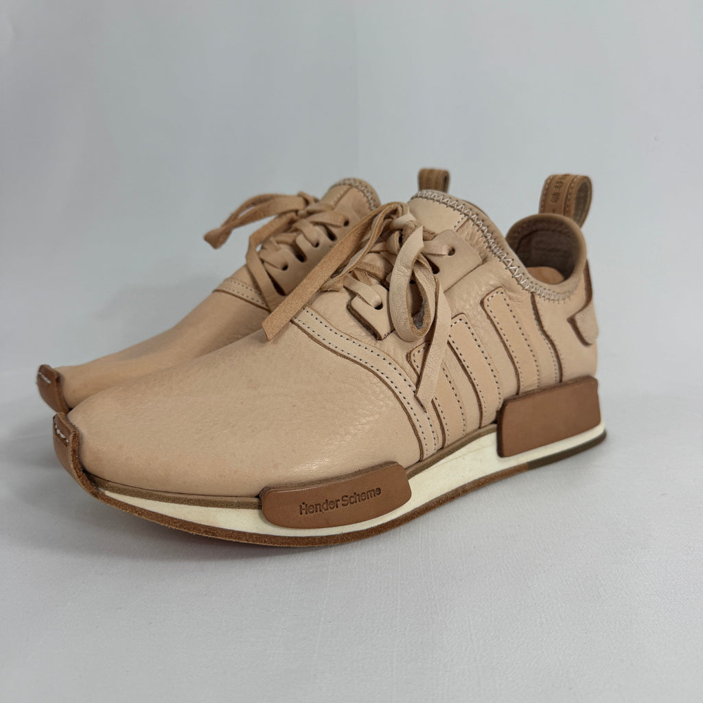 The Adidas x Hender Scheme NMD R1 is a premium collaboration that reimagines the iconic NMD with handcrafted natural leather