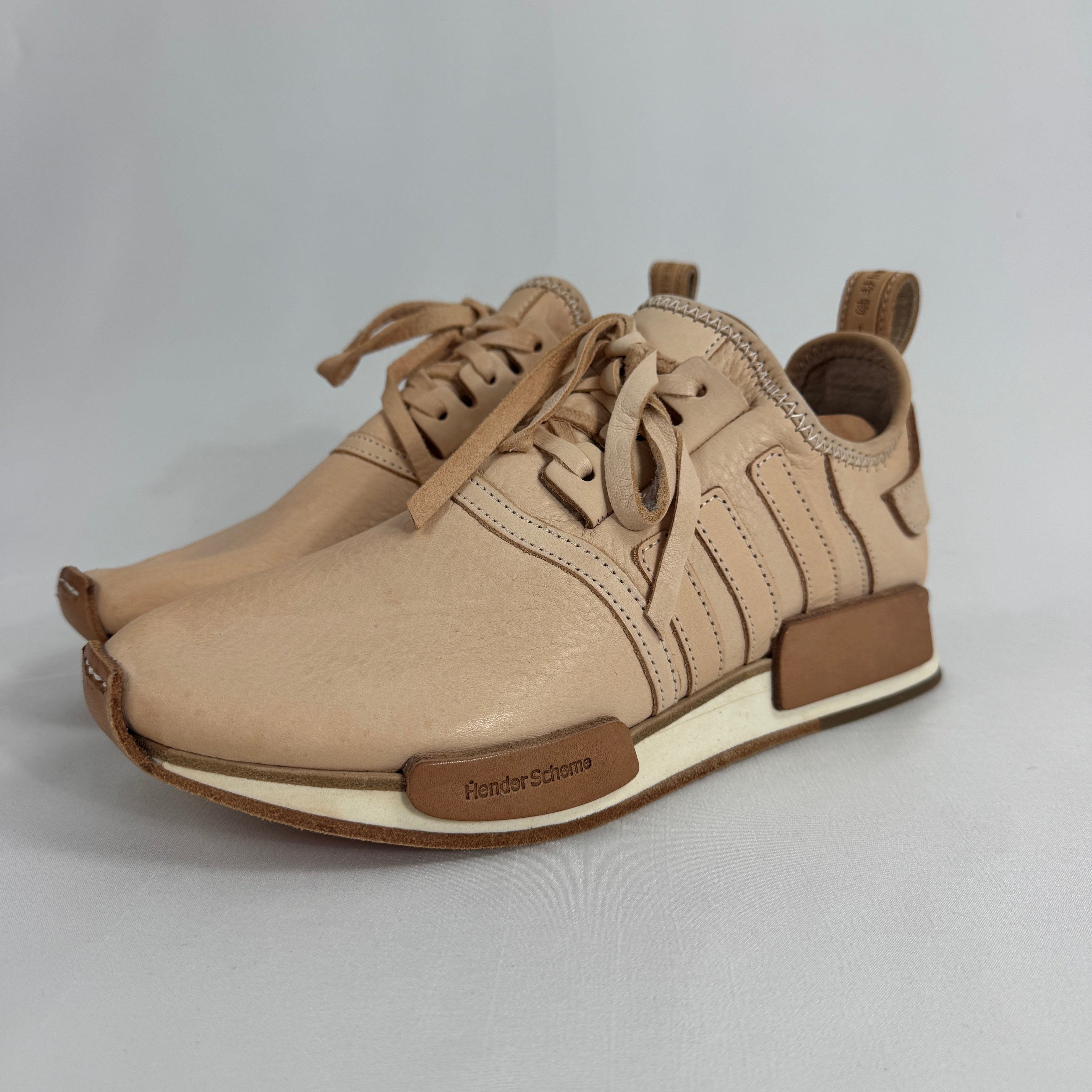 The Adidas x Hender Scheme NMD R1 is a premium collaboration that reimagines the iconic NMD with handcrafted natural leather