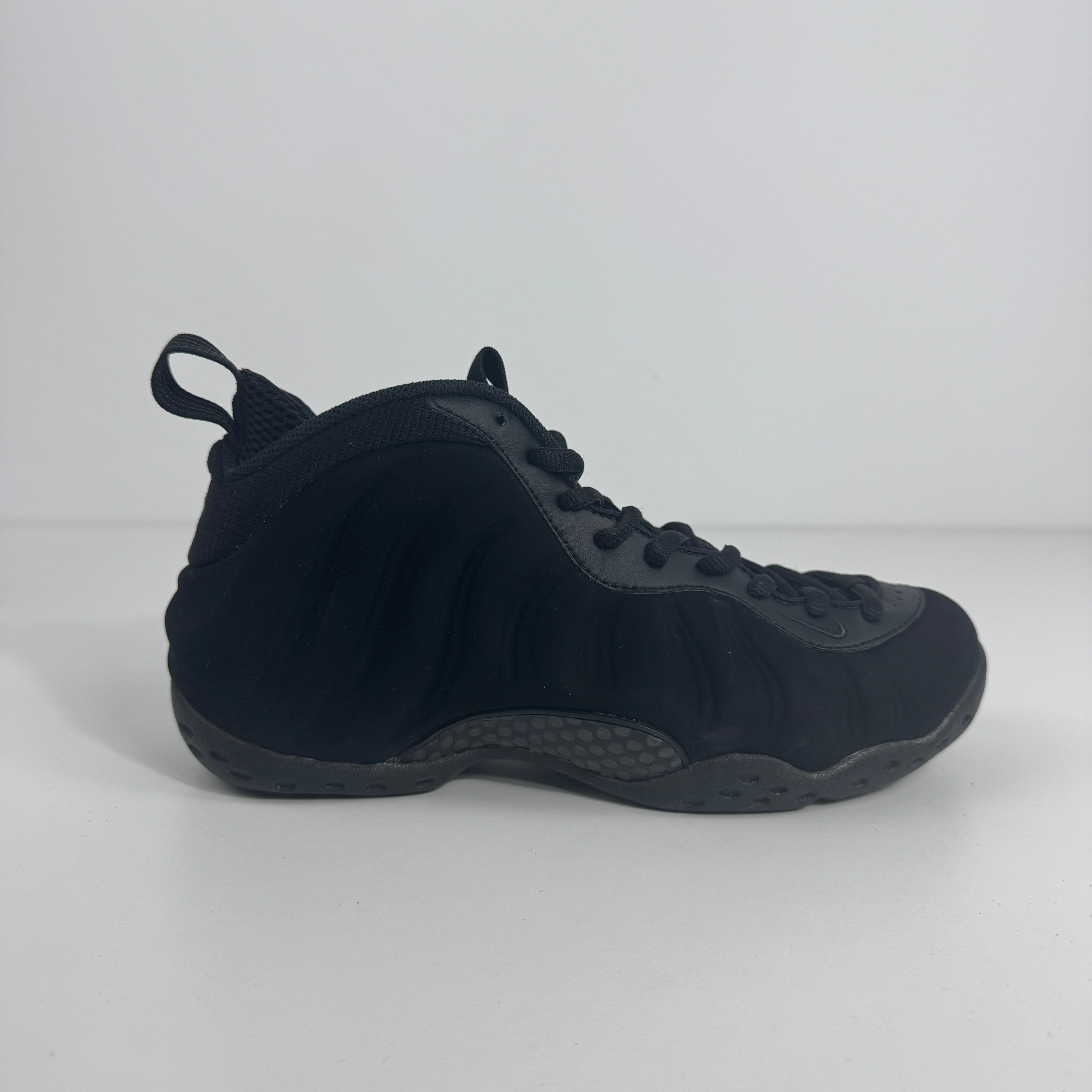 A black Nike basketball trainer with wavy detail, textured sole, Zoom Air cushioning and heel pull tab on a white background.