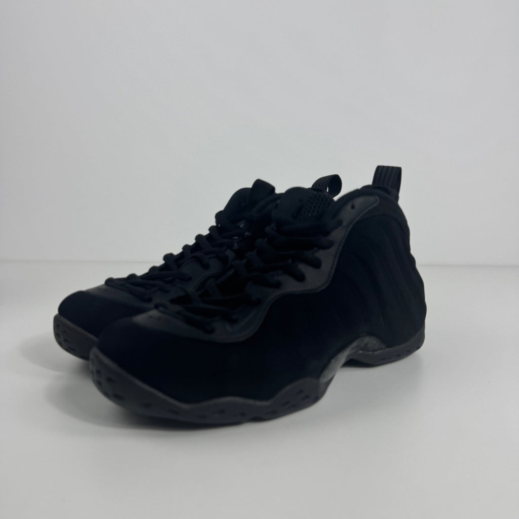 A pair of black Nike basketball trainers with lace-up fronts and textured soles is shown on a white surface with a white background.
