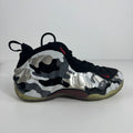 Nike trainer with a black, white and grey camo upper, black laces and trim, red details, and a translucent yellow-toned sole on white background.