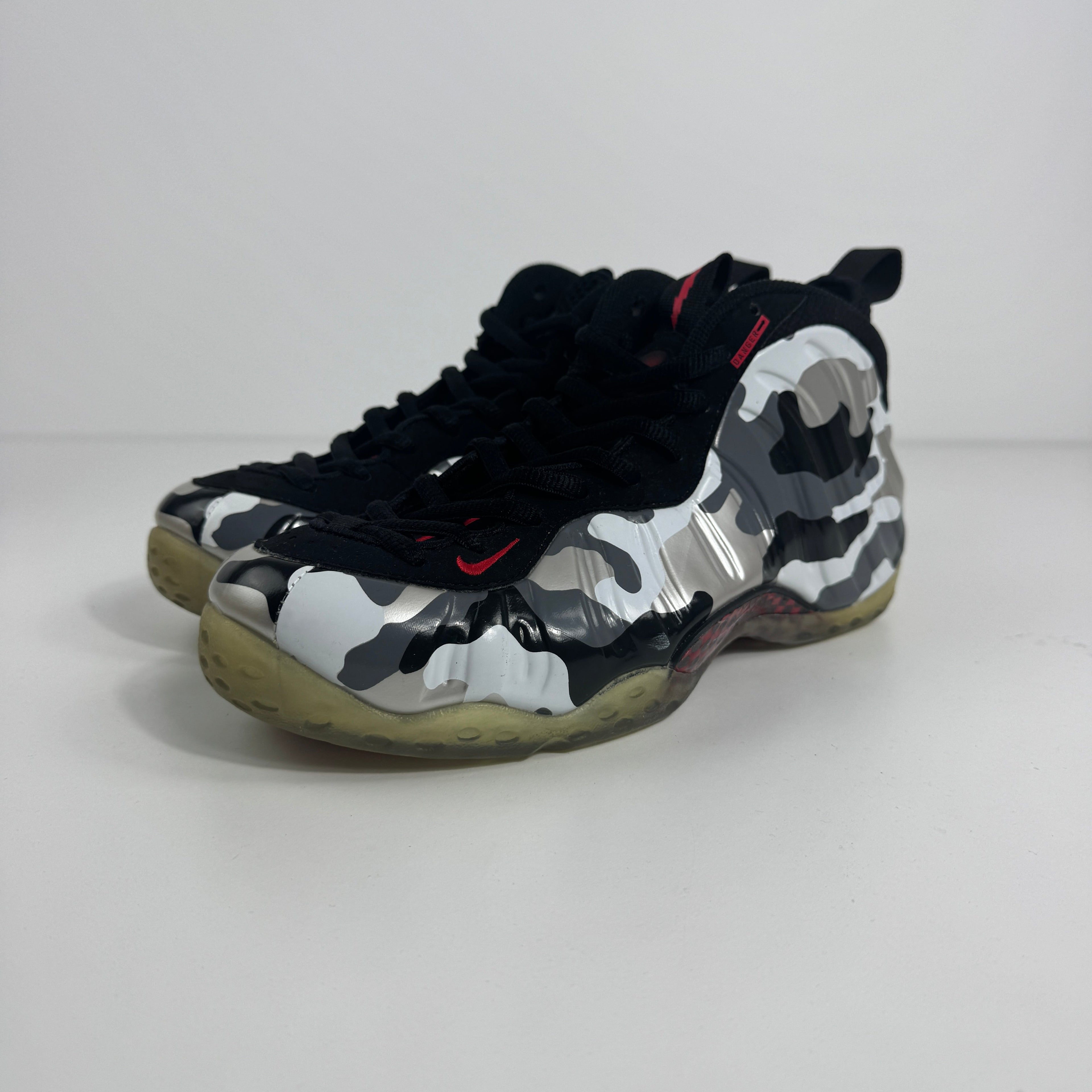 Nike Air Foamposite One PRM trainers in black, white and grey camo with translucent yellow soles on a plain white background.