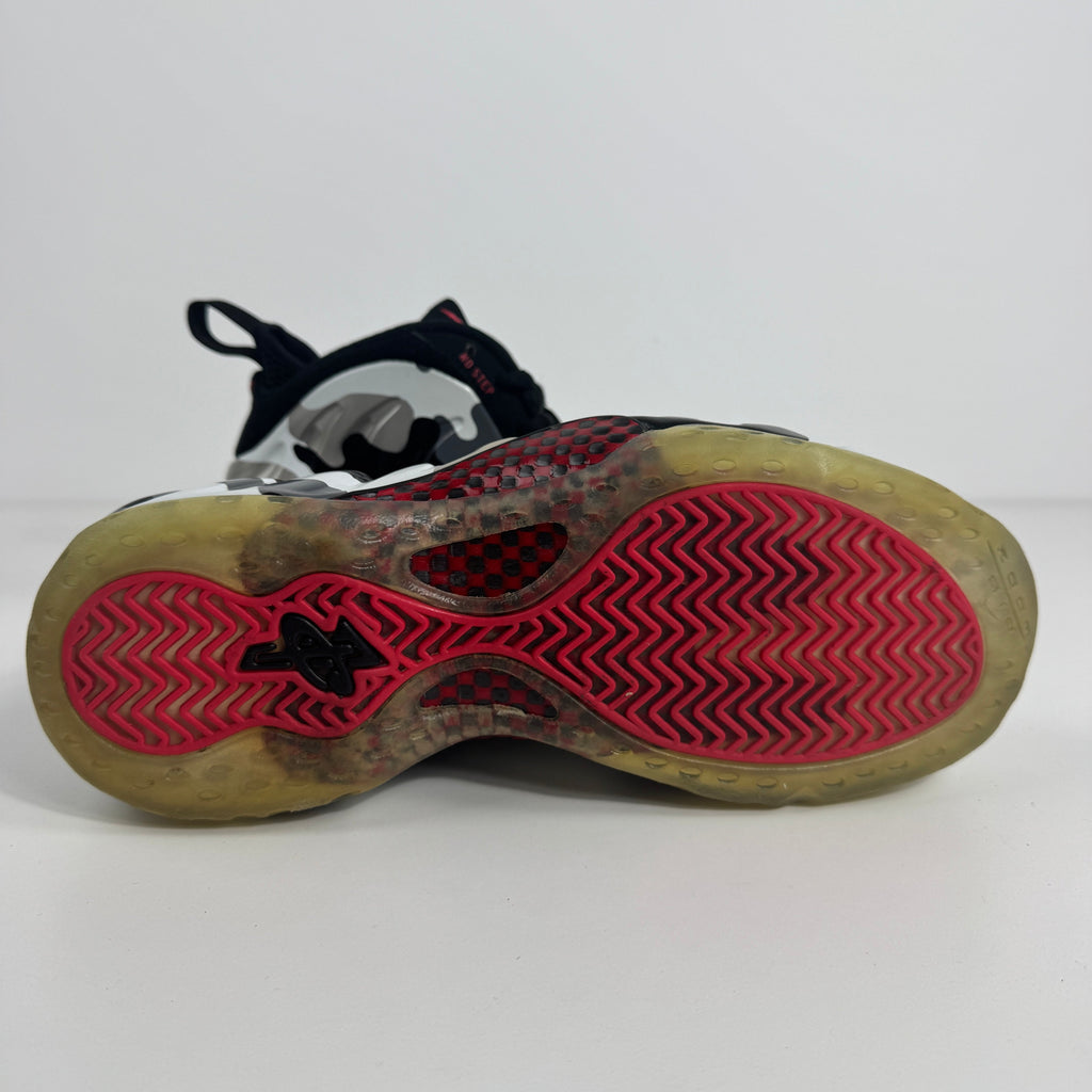 Close-up of a Nike trainer sole with a see-through rubber base, red zigzag tread and black detailing, on a plain white background.