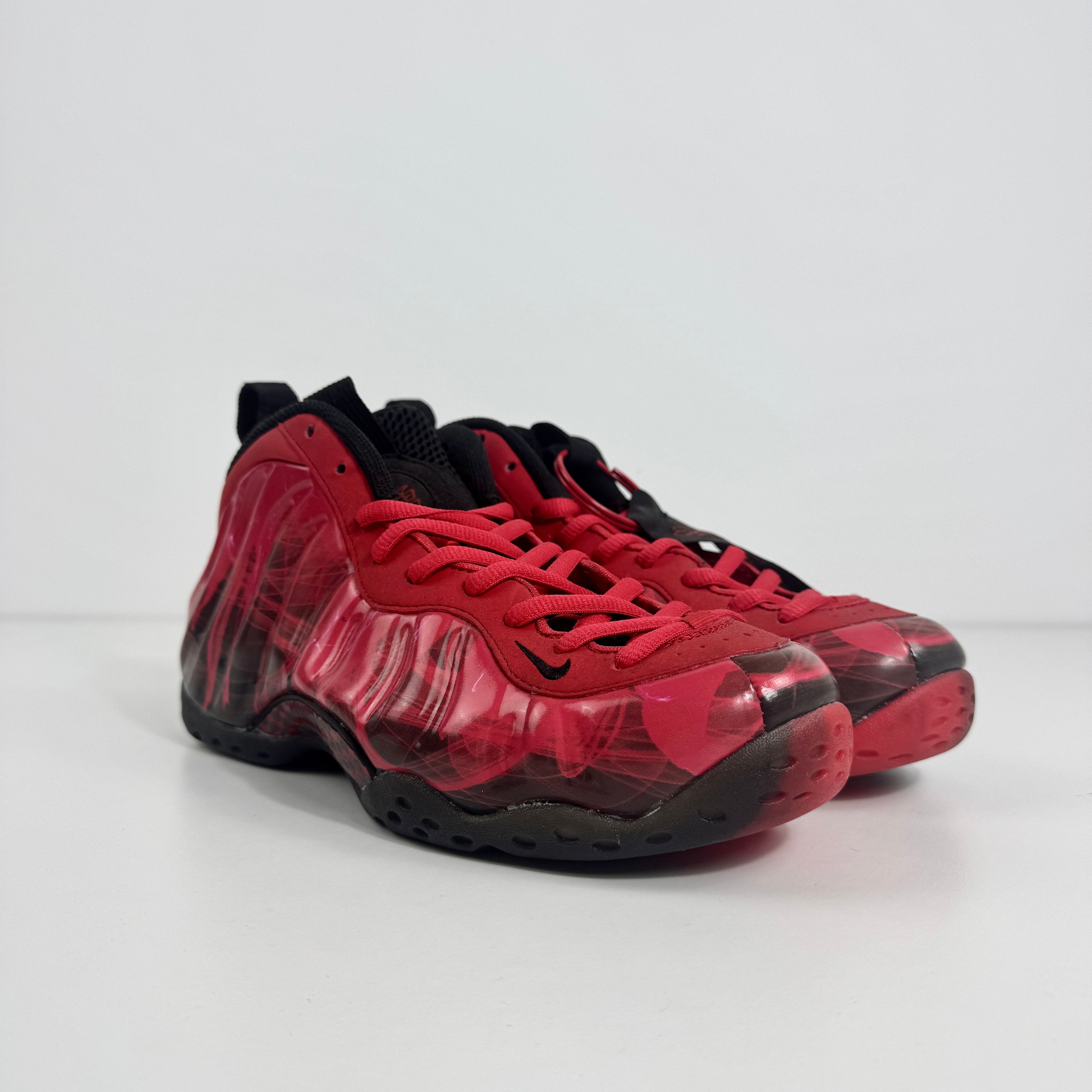 Nike trainers with a glossy red and black wavy pattern and black laces, shown against a plain white background.