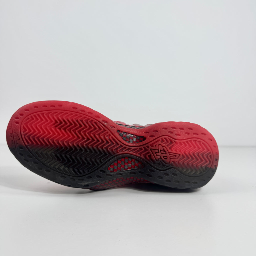 Sole of a Nike trainer in red and black gradient with herringbone grip pattern and logo at the centre, on a white background.