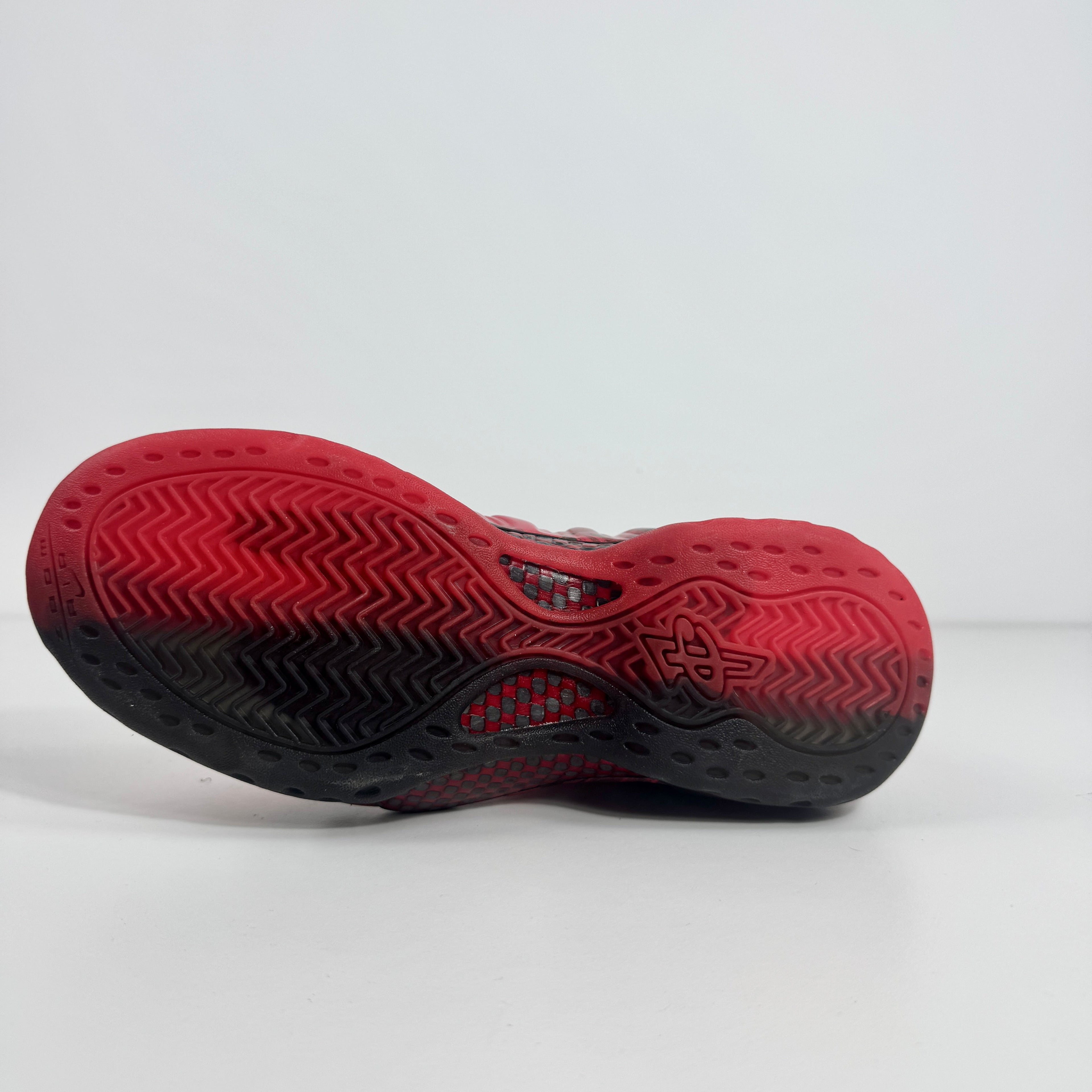 Sole of a Nike trainer in red and black gradient with herringbone grip pattern and logo at the centre, on a white background.