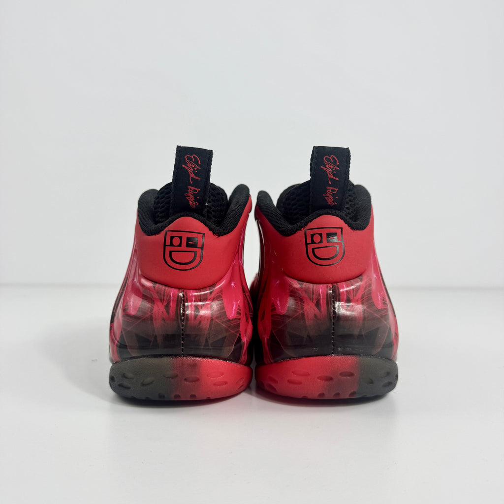 Nike Air Foamposite trainers in red and black with smiley faces on the heels, black pull tabs, and circular patterned soles.