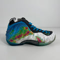 Nike trainers with a white base, blue laces, and bold multicoloured abstract patterns in green, pink and blue.