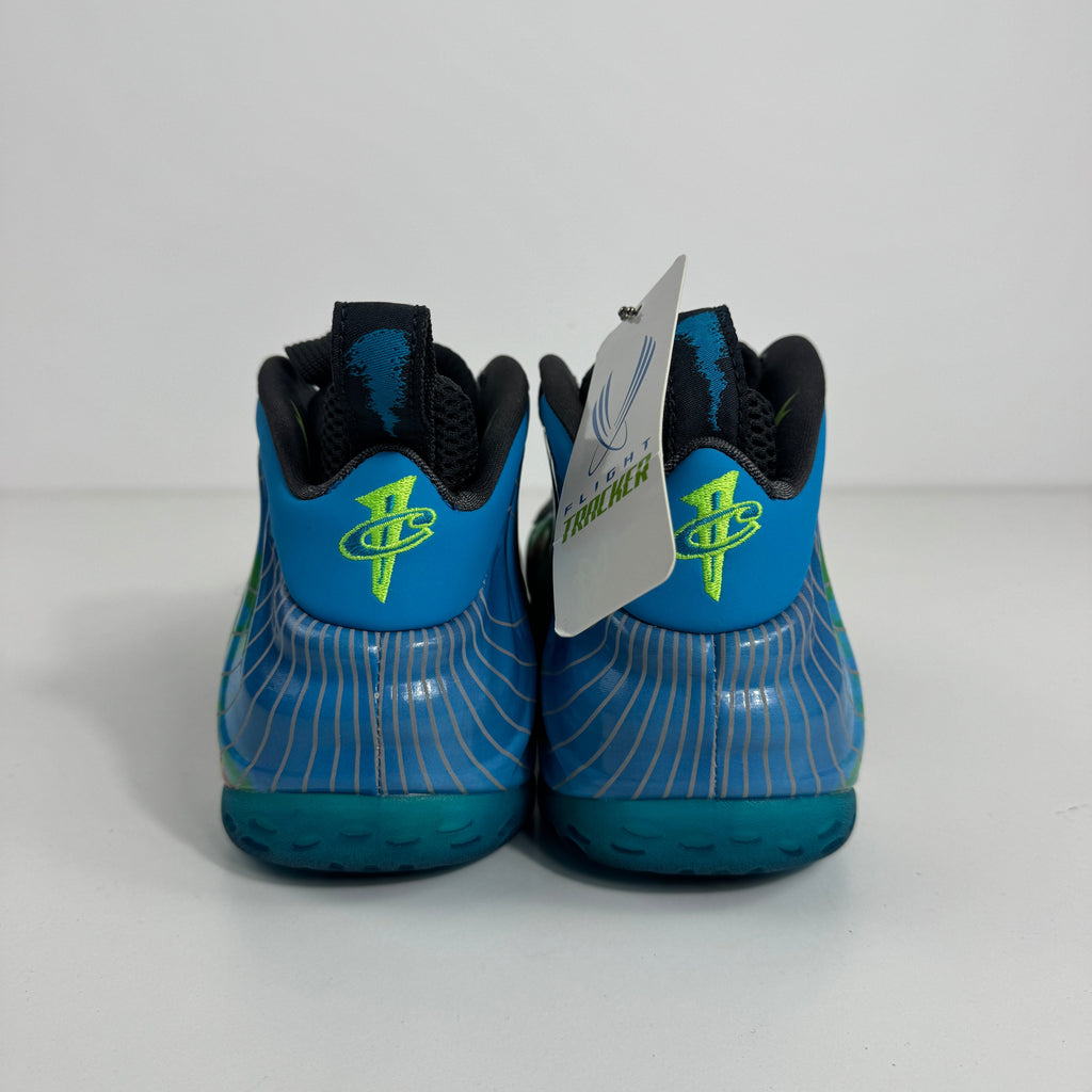 Nike Air Foamposite One trainers in blue with neon green logos, wavy white detailing and a branded tag, shown from the back.