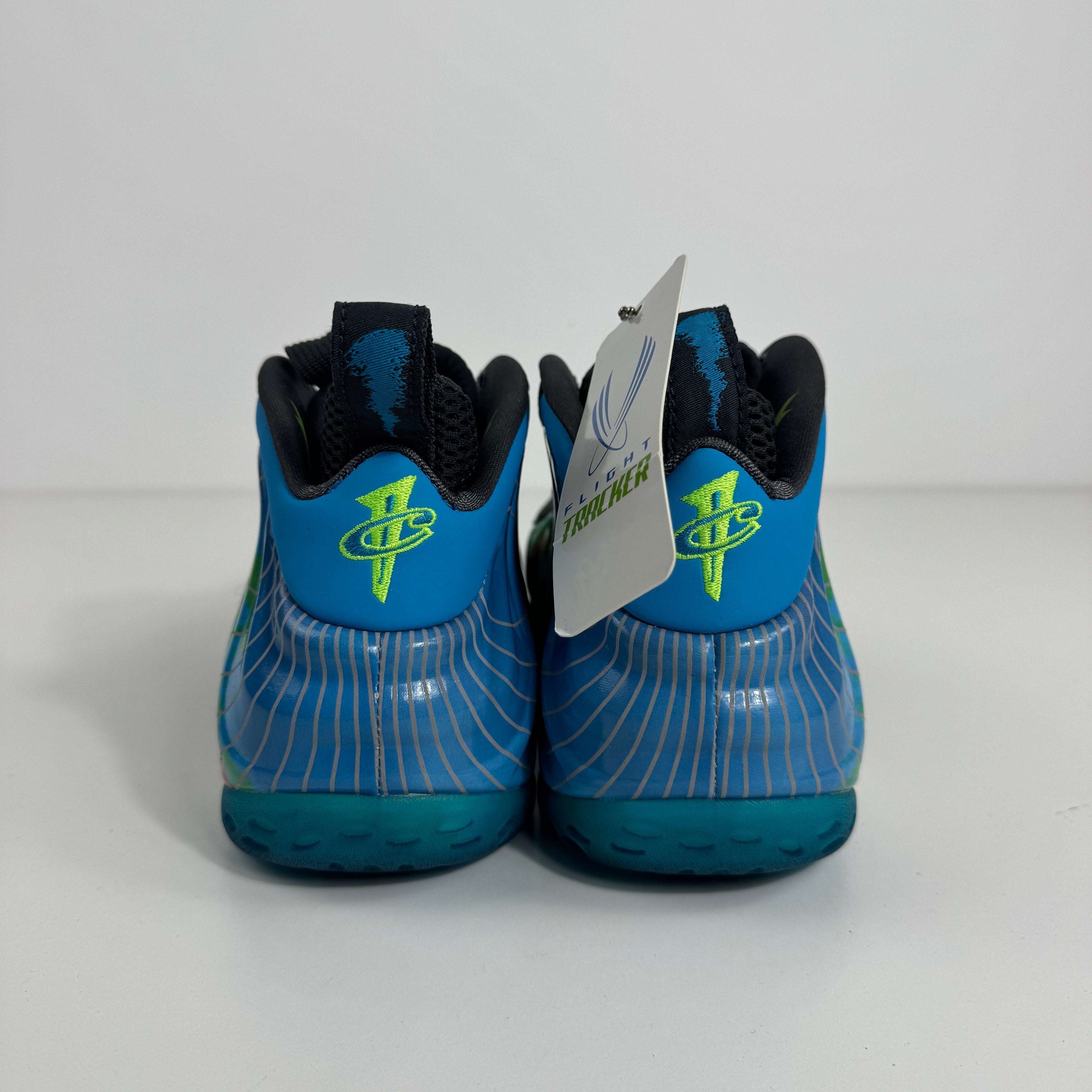 Nike Air Foamposite One trainers in blue with neon green logos, wavy white detailing and a branded tag, shown from the back.