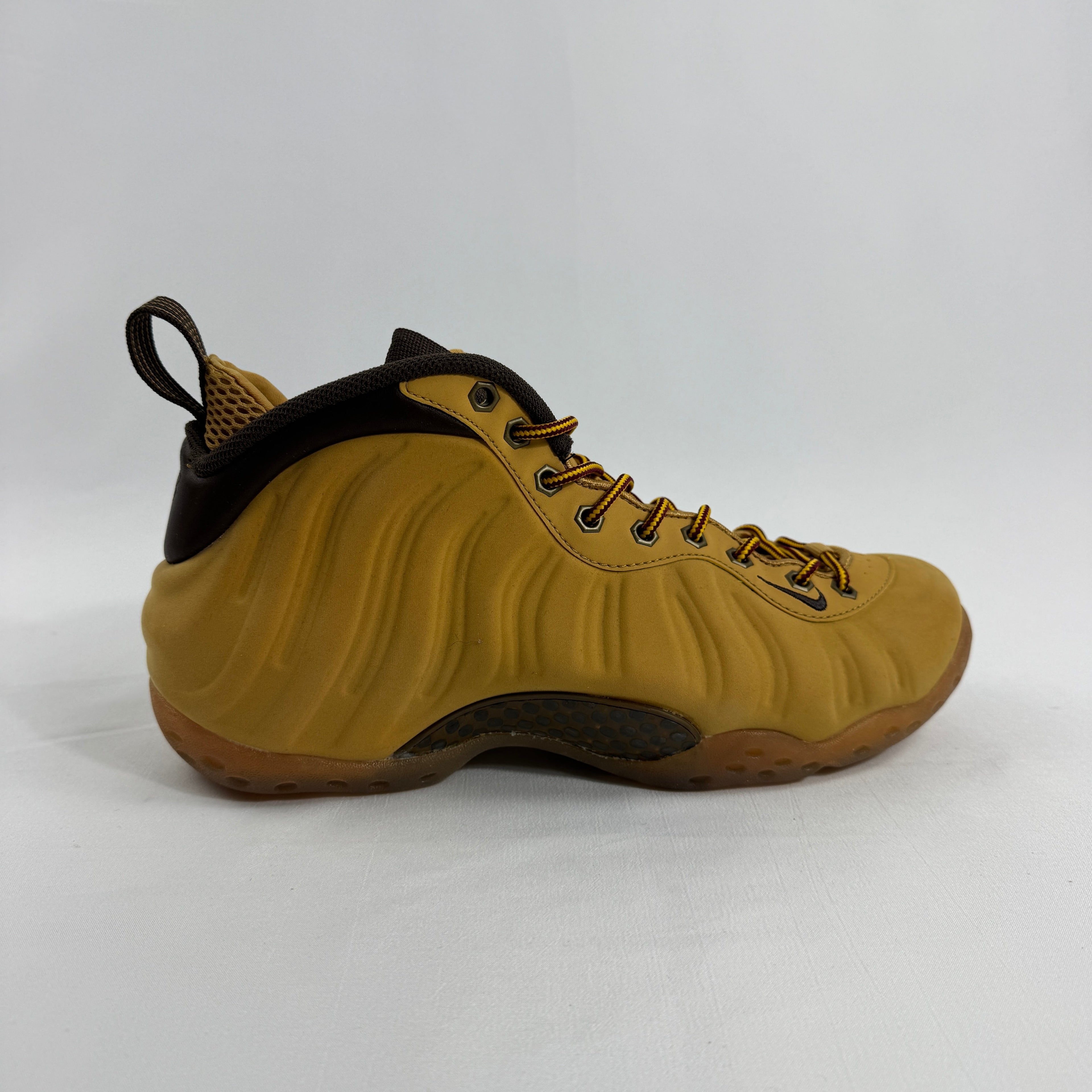 A tan and brown Nike trainer with a wavy side design, dark laces, brown collar, and gum sole on a plain white background.