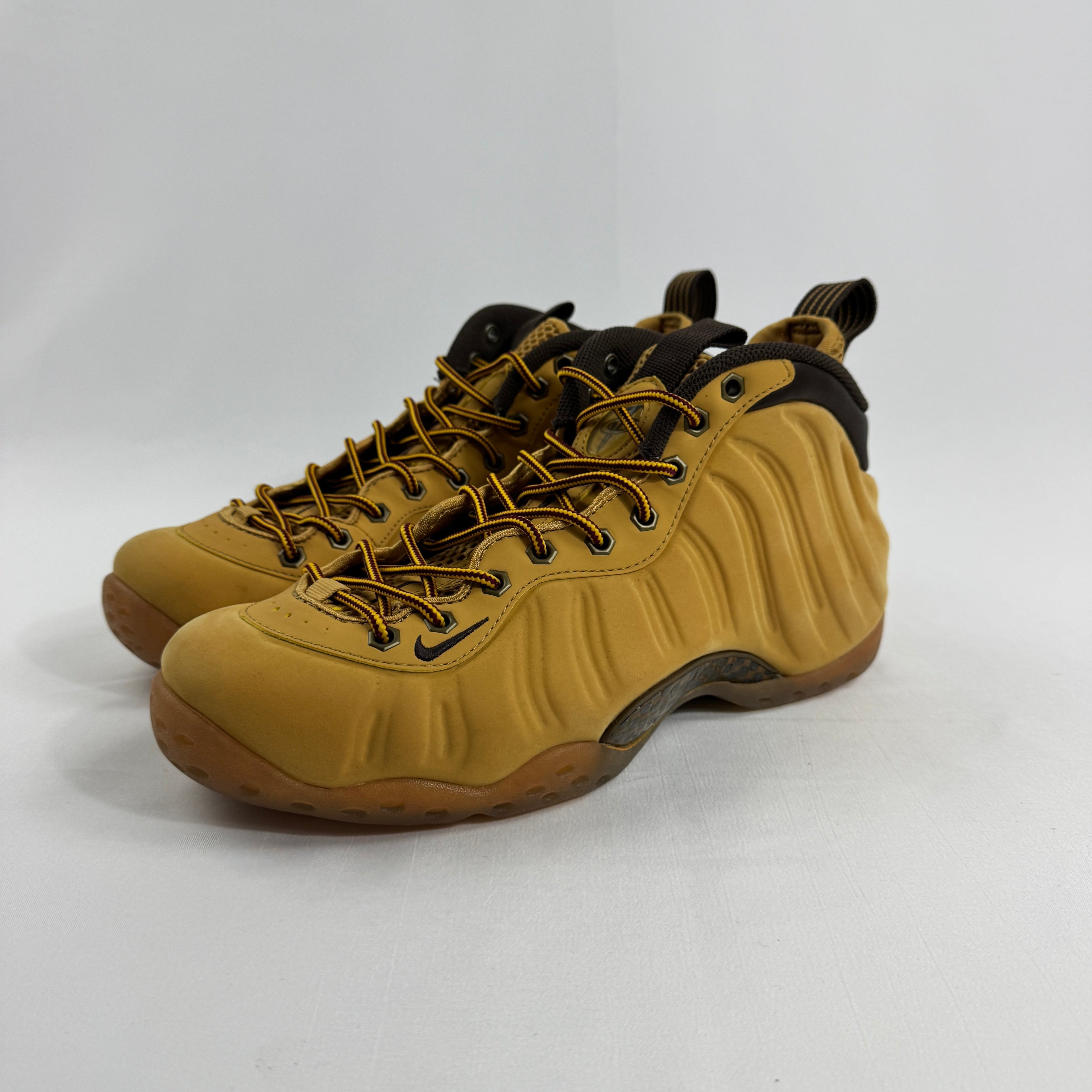 NIKE trainers in tan and brown with textured sides, brown laces, and pull tabs on the tongue and heel, on a white background.