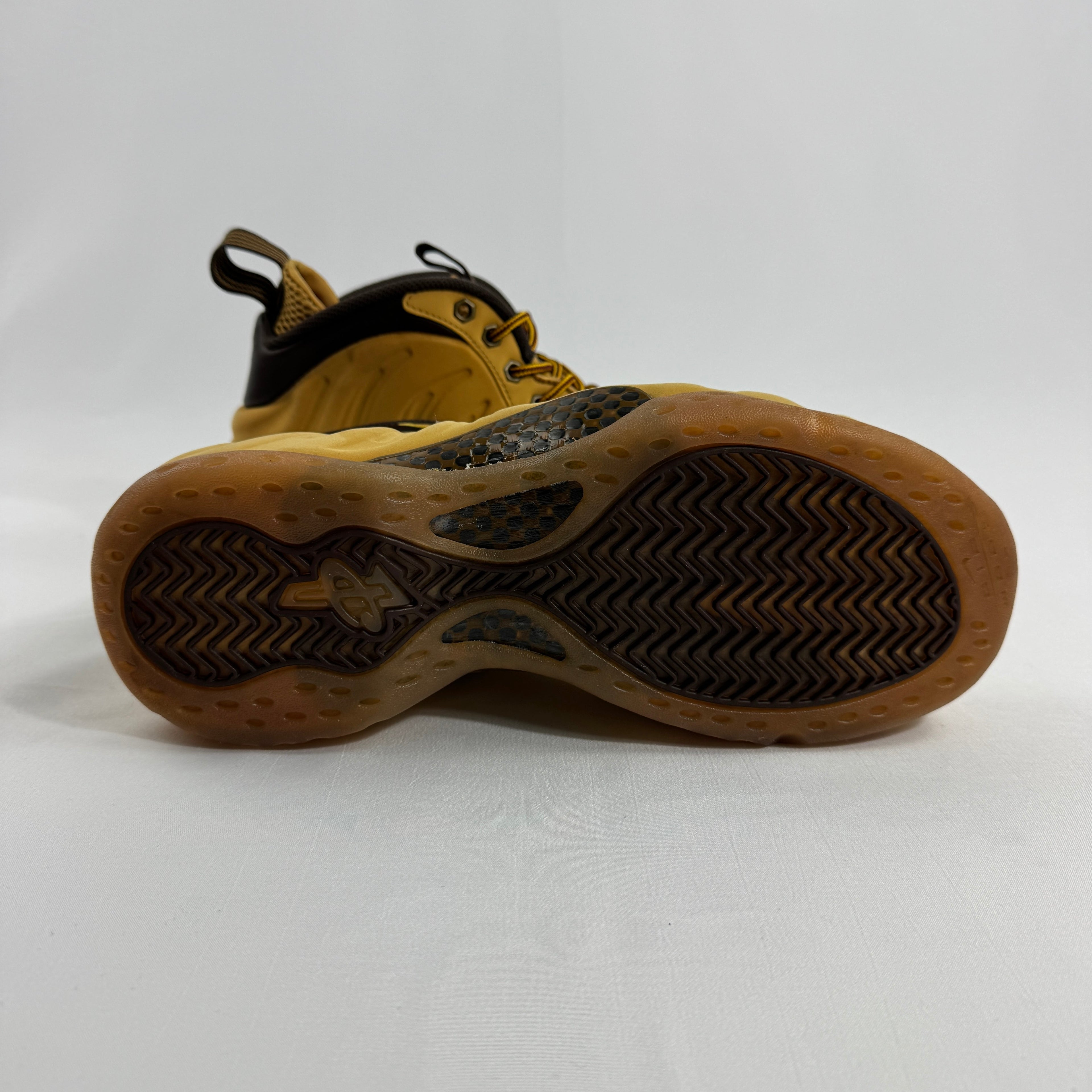 Bottom view of a Nike trainer in wheat colour with a textured yellow and black sole featuring wavy zigzag patterns.