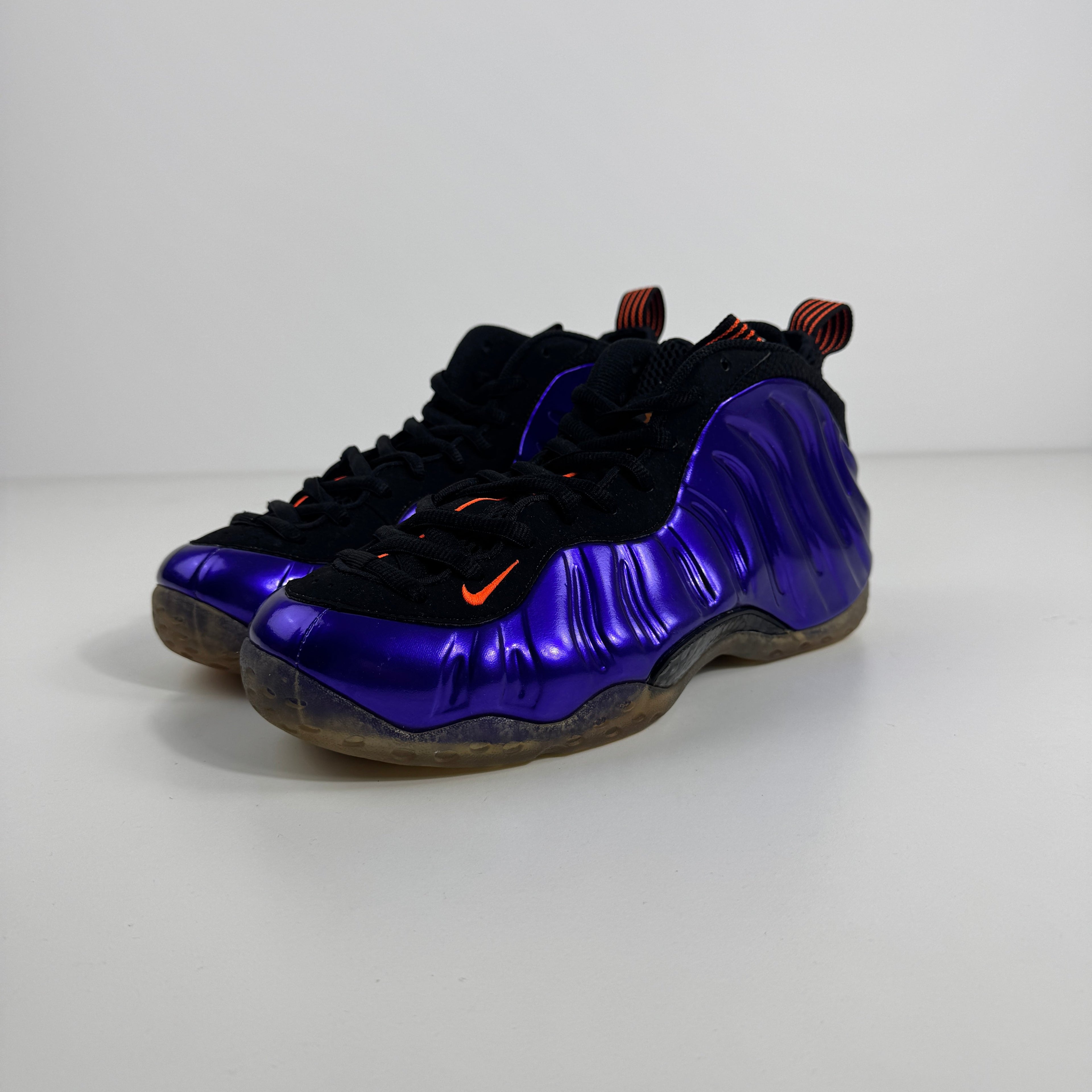 Nike basketball trainers with a glossy purple shell, black accents, orange details and translucent soles on a white background.