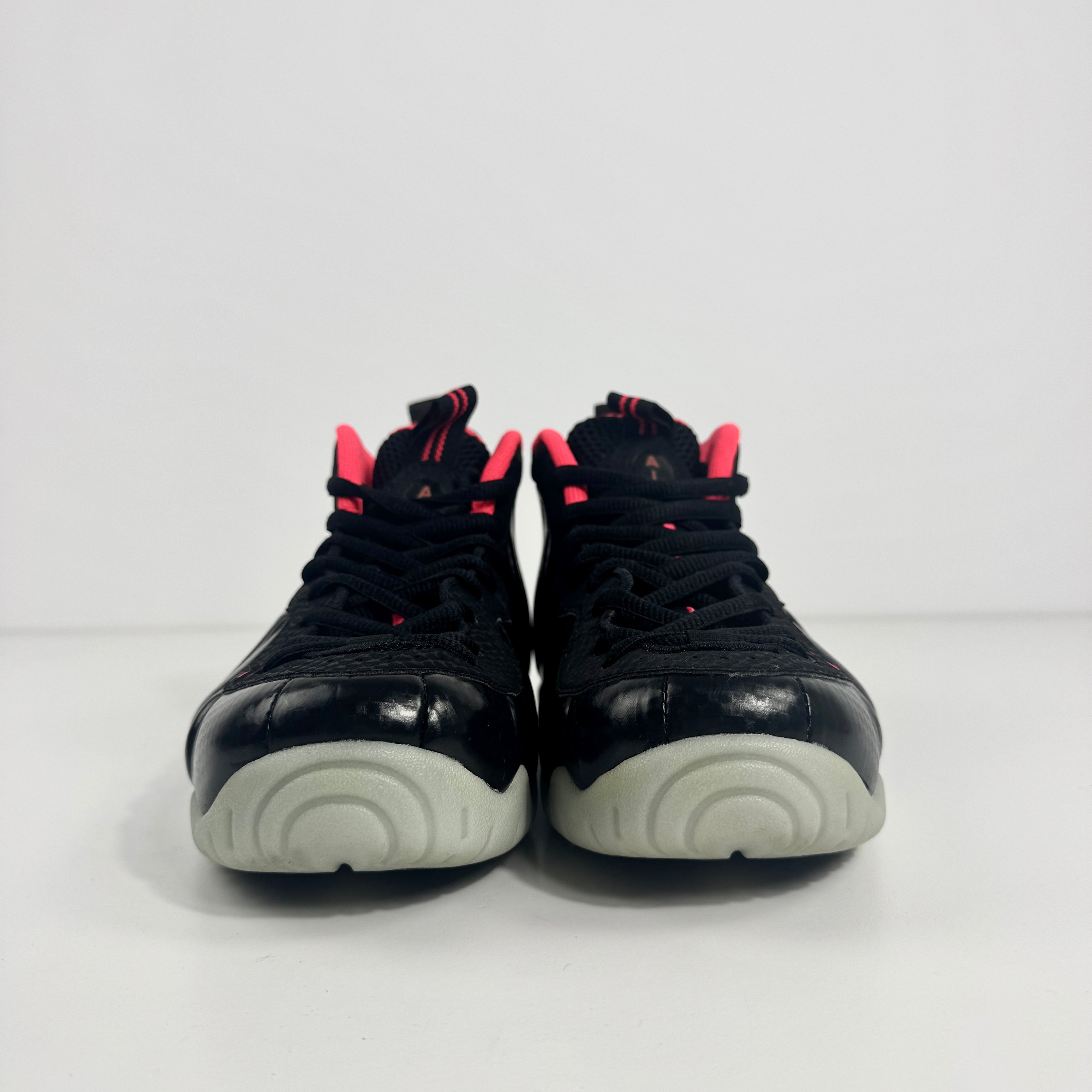 Nike Air Foamposite Pro sneakers with black moulded uppers, red detailing and light grey soles, shown side by side on white background.