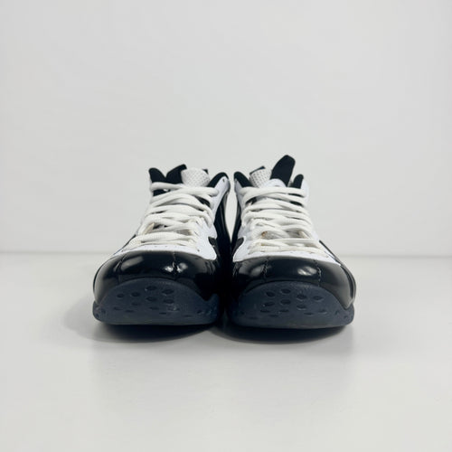 The Nike Air Foamposite One Concord UK 7 features a shiny black molded upper paired with stark white leather trim along the