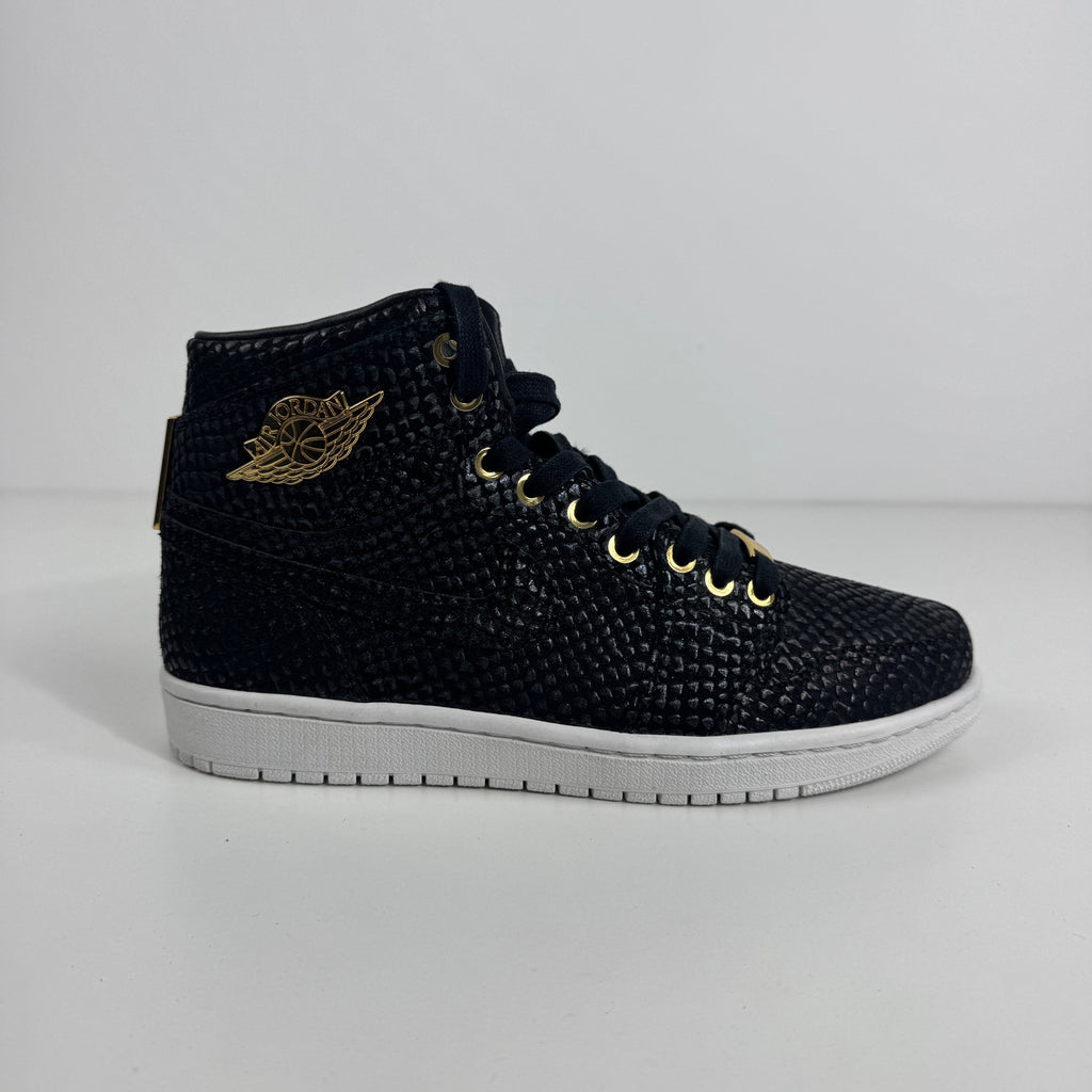 Black Nike high-top trainer with snakeskin texture, gold eyelets and wing logo, and a white rubber sole on a white background.