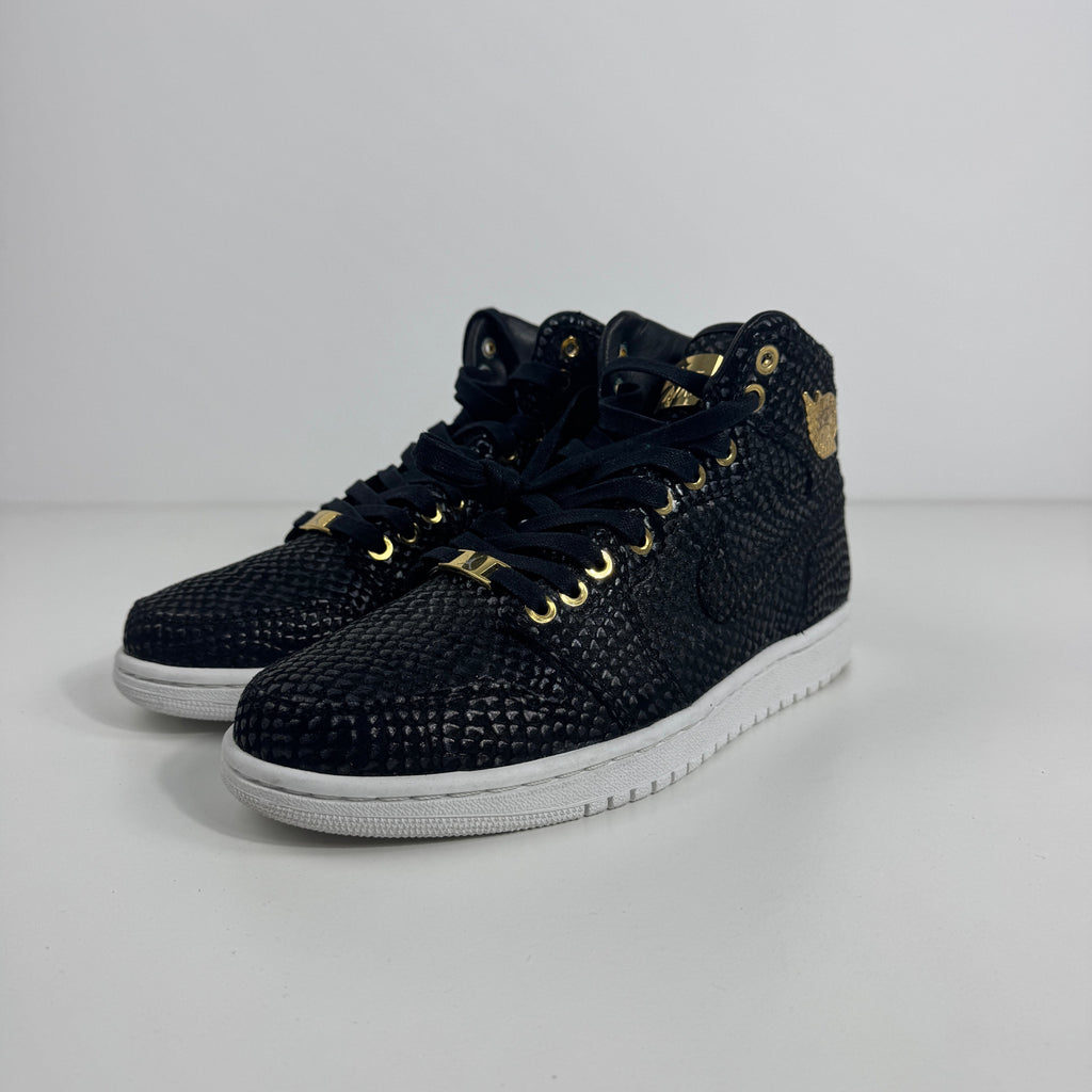 Nike Air Jordan 1 Pinnacle trainers in black textured material with gold accents, black laces and white soles on a white background.