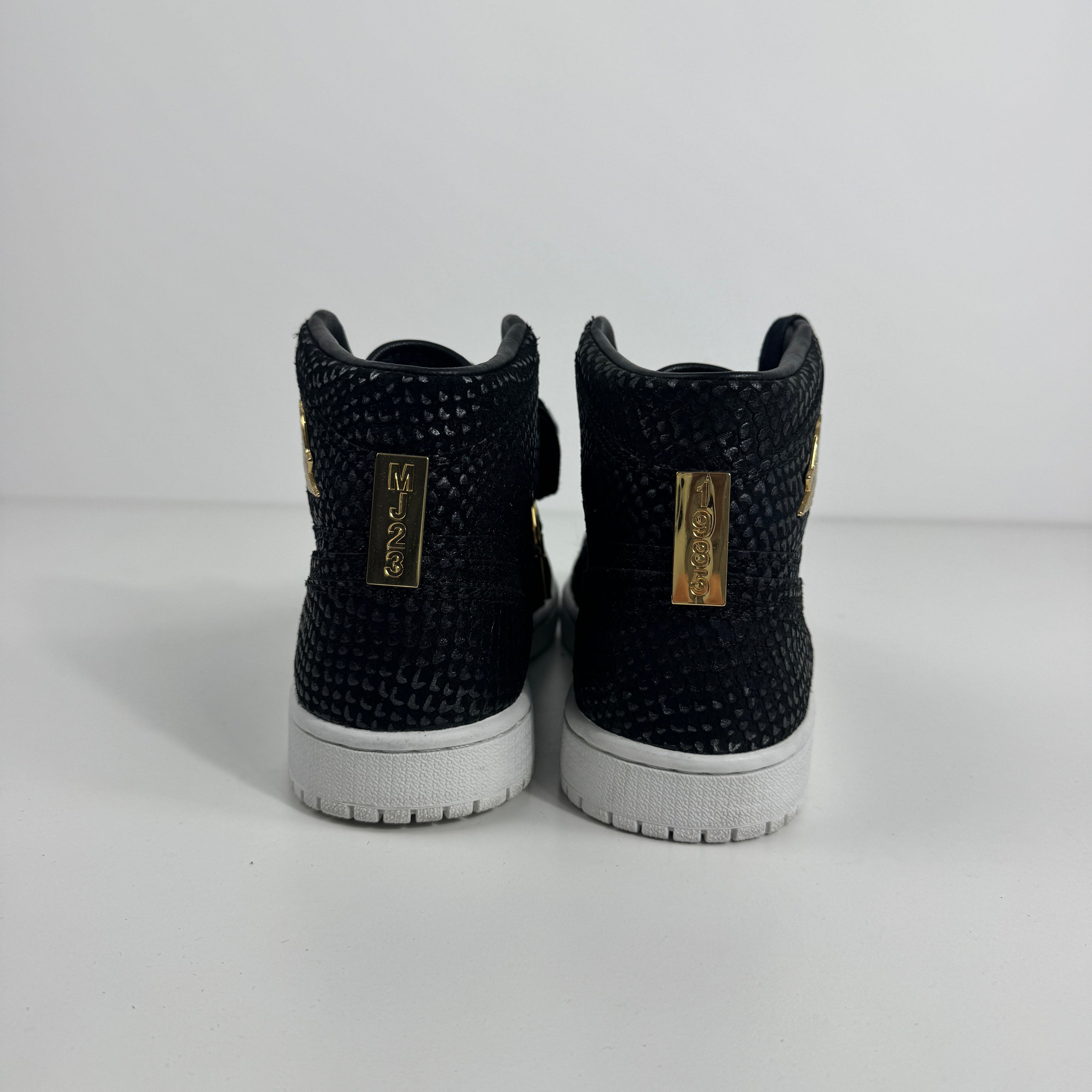 Black textured Nike high-top trainers with white soles and gold MJ23 tags on the heel, displayed against a white background.