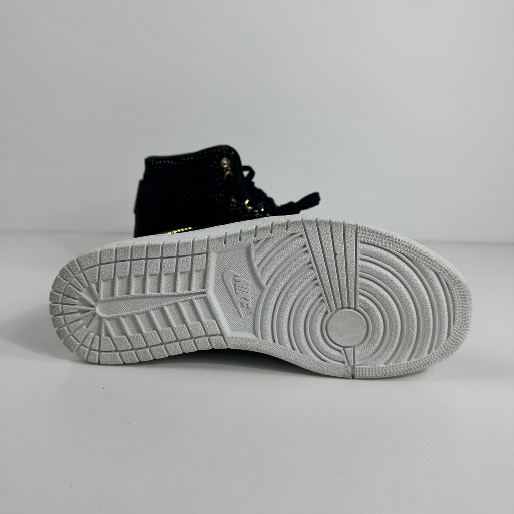 Black NIKE Air Jordan 1 trainer shown side-on, highlighting the white sole with circular and linear treads on a plain background.