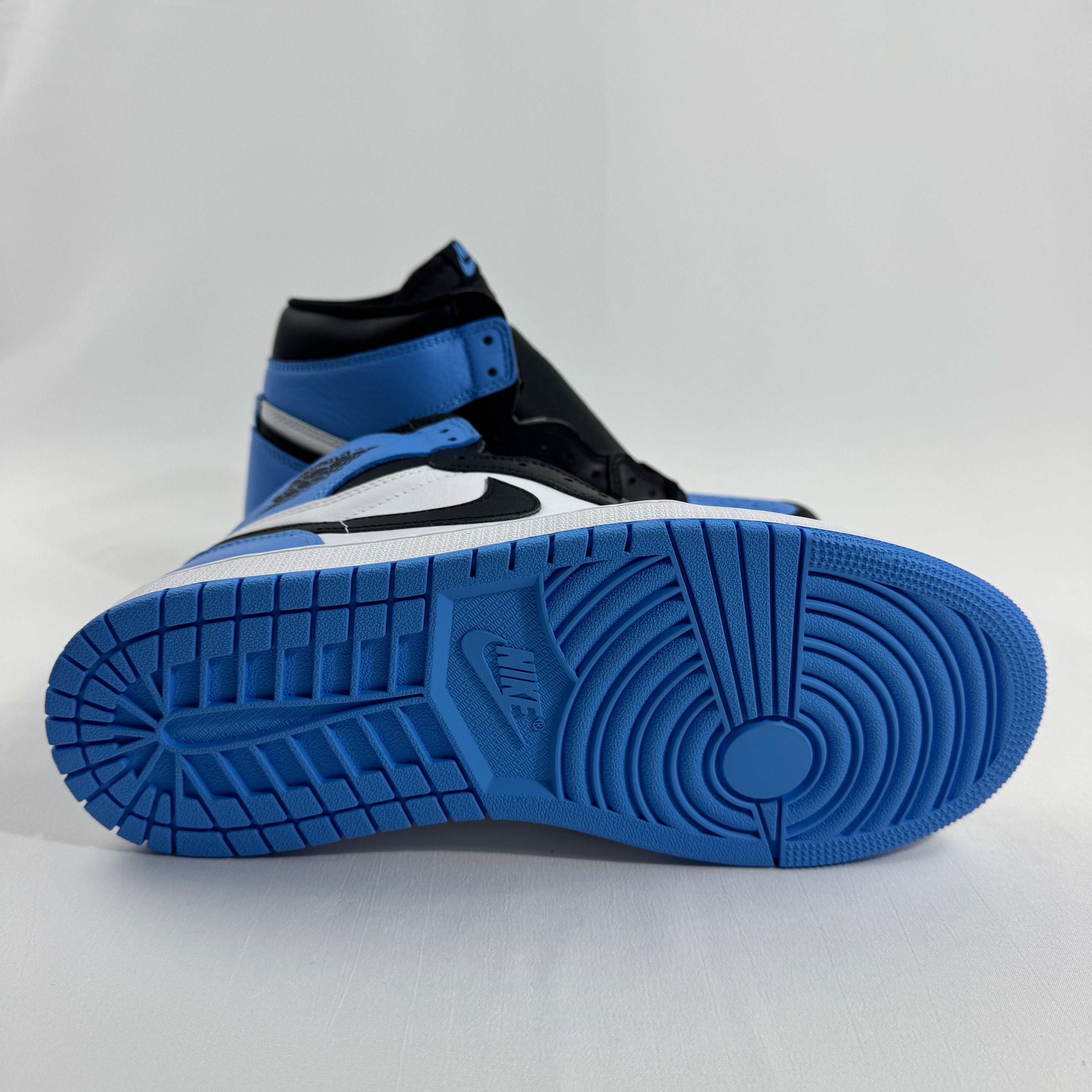 NIKE high-top trainers in black, white and blue on a white background, with one shoe upright and the other showing its blue sole.