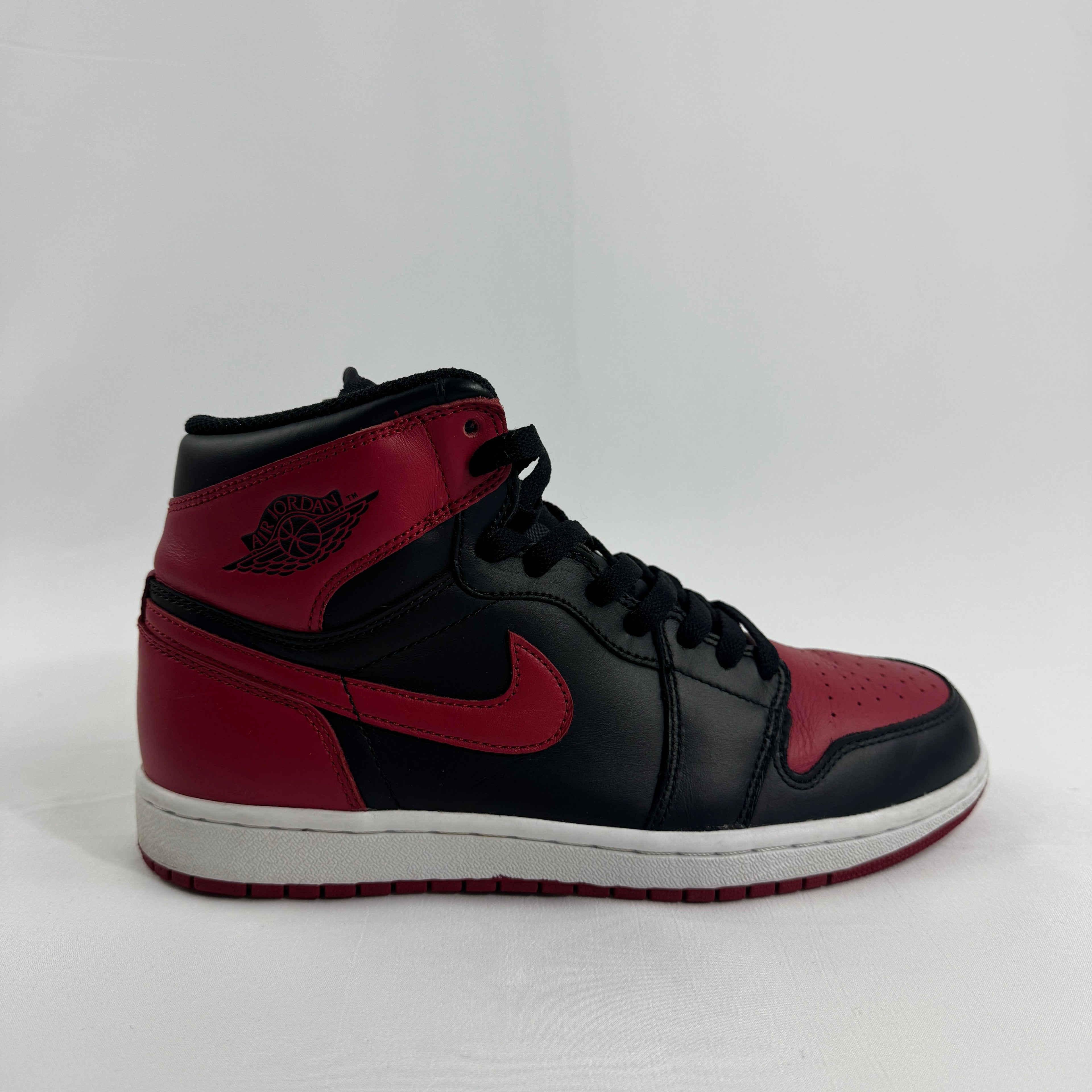 Side view of a black and red Nike Air Jordan trainer with the swoosh and wings emblem, set against a plain white background.