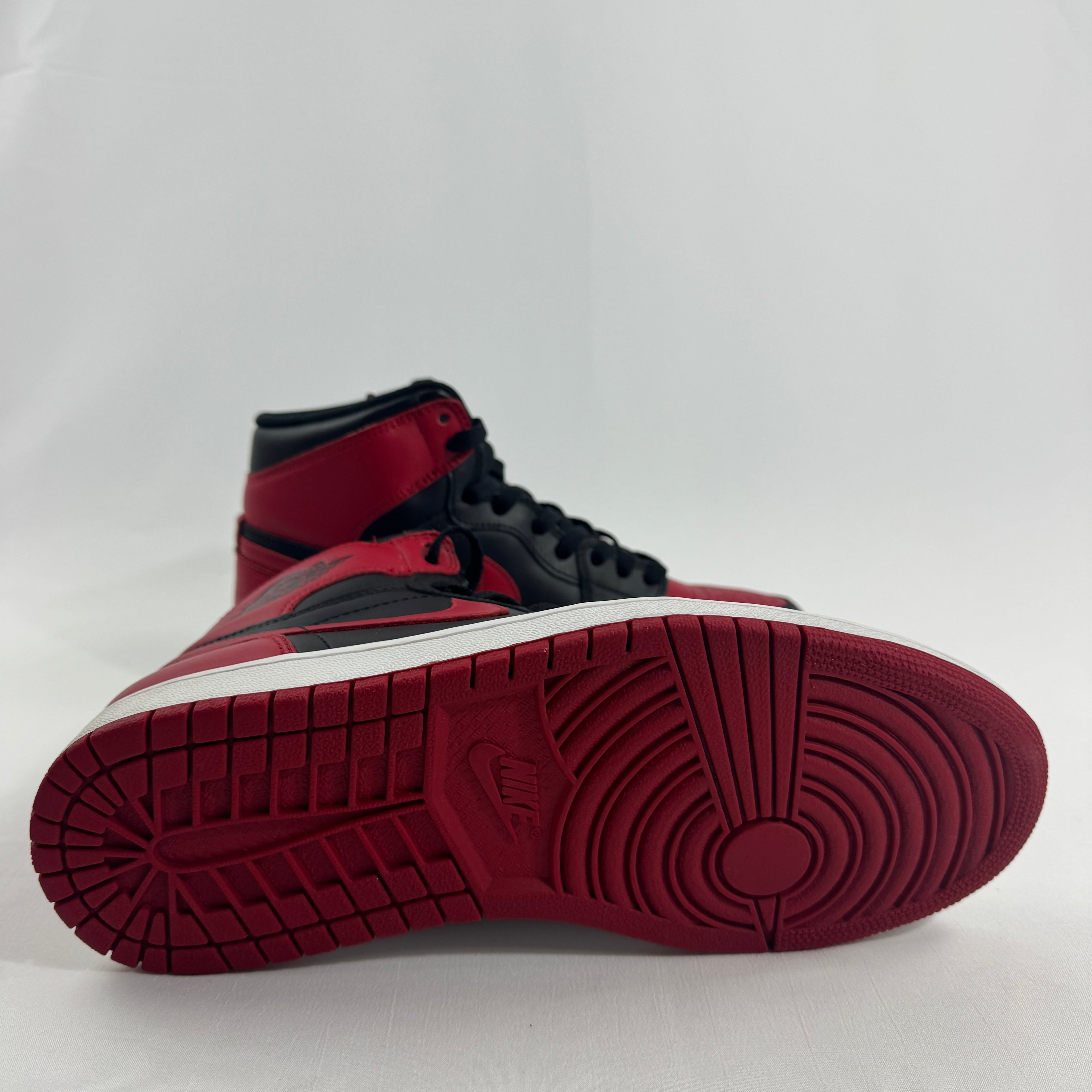 A pair of black, red and white Nike Air Jordan trainers on a plain white background, one upright and one lying on its side.
