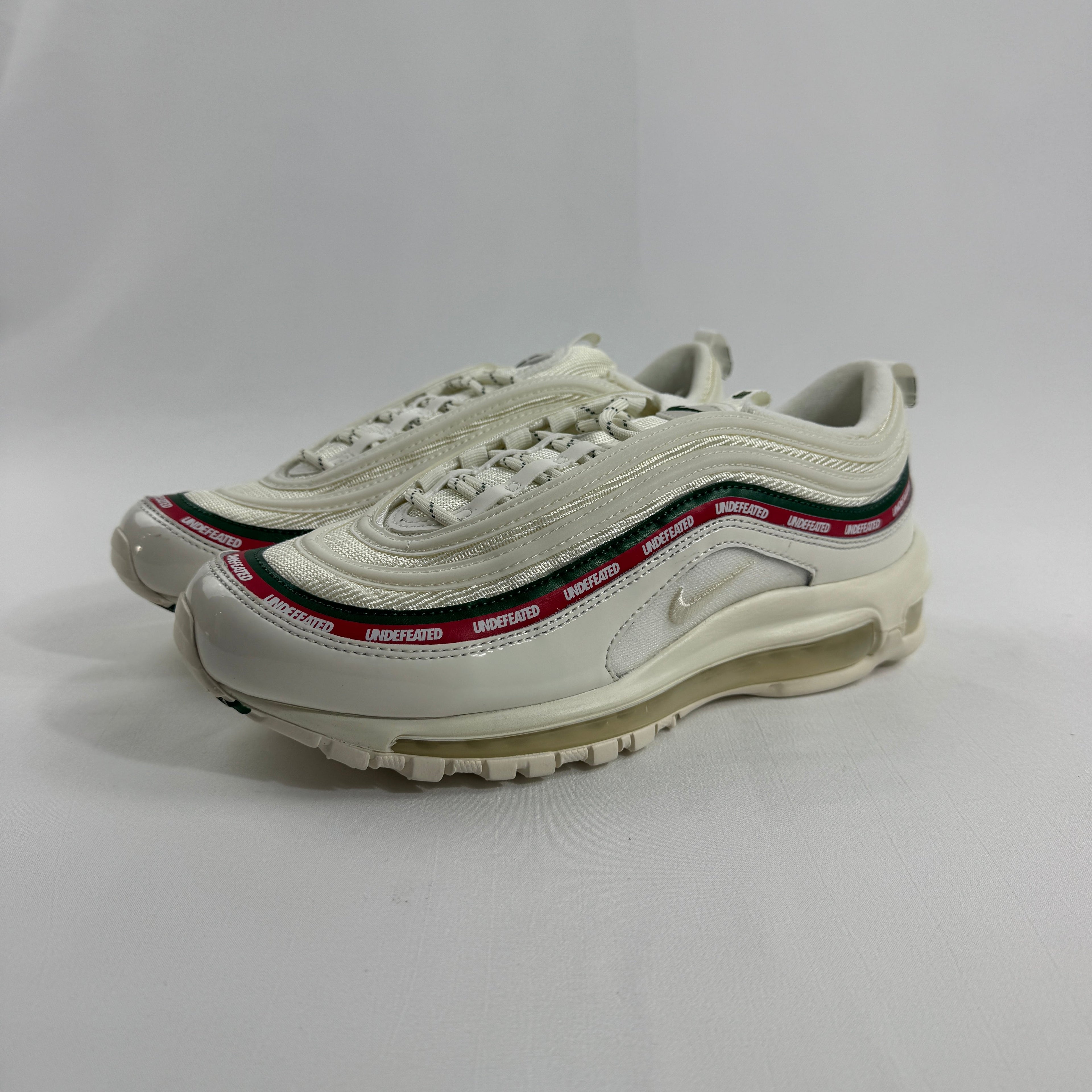 NIKE Air Max 97 Undefeated Sail trainers with cream soles and red, black and green accents on a plain white background.
