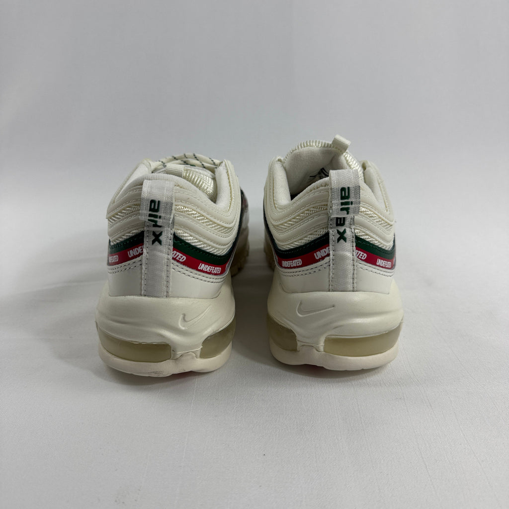 NIKE Air Max 97 Undefeated Sail trainers with white uppers, green and red stripes, and Undefeated detail on the heel, rear view.