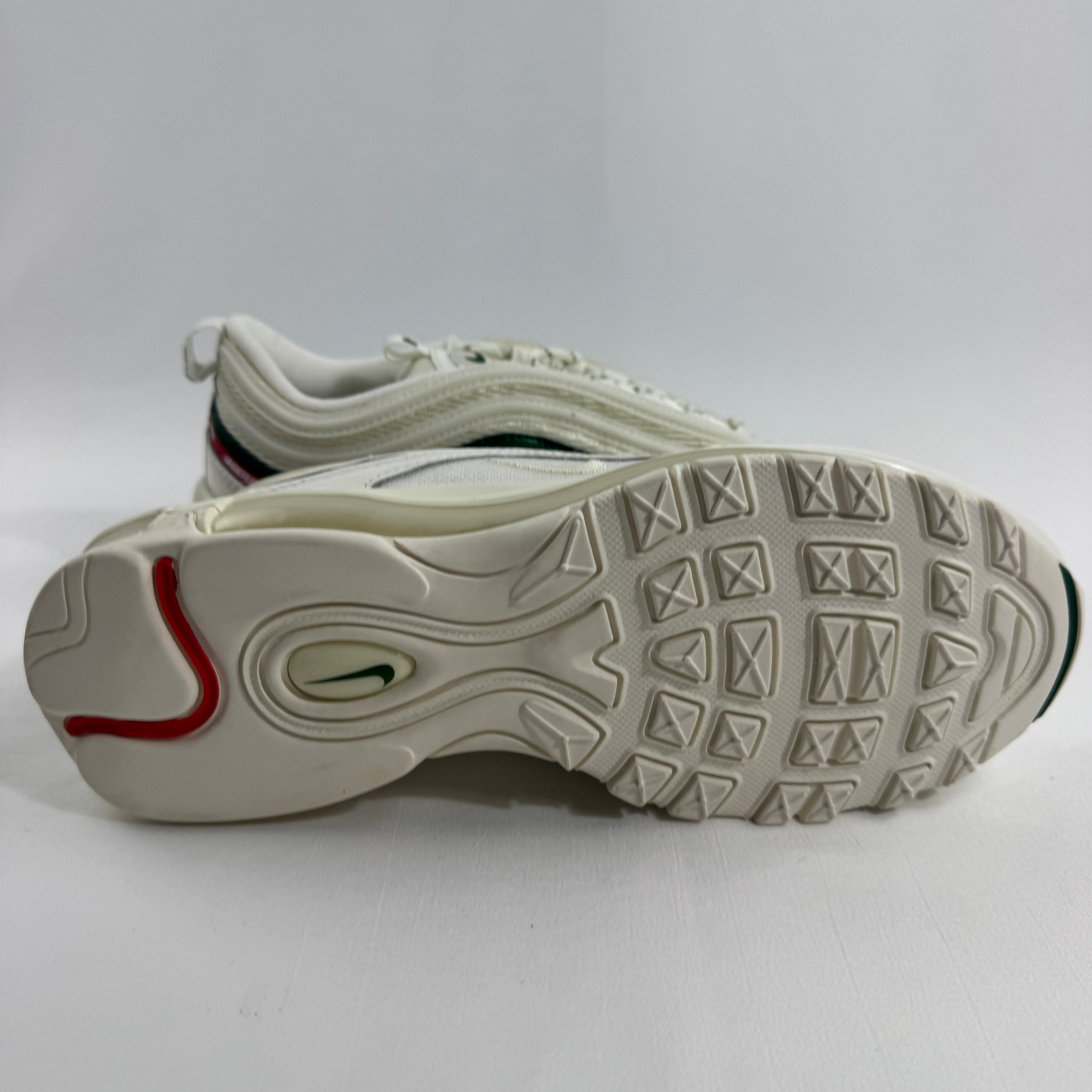 Nike Air Max 97 Undefeated Sail trainers on a white background, one upright and one side-on showing red and green outsole details.