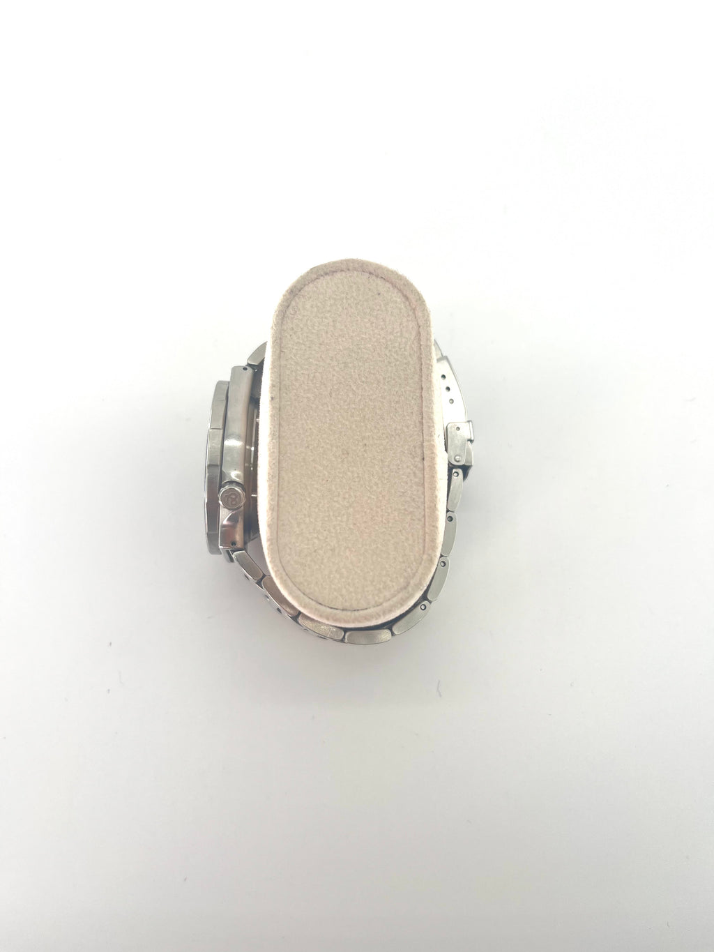 A Bell and Ross silver wristwatch with a round face is displayed on a beige cushion, shown with additional interchangeable straps.