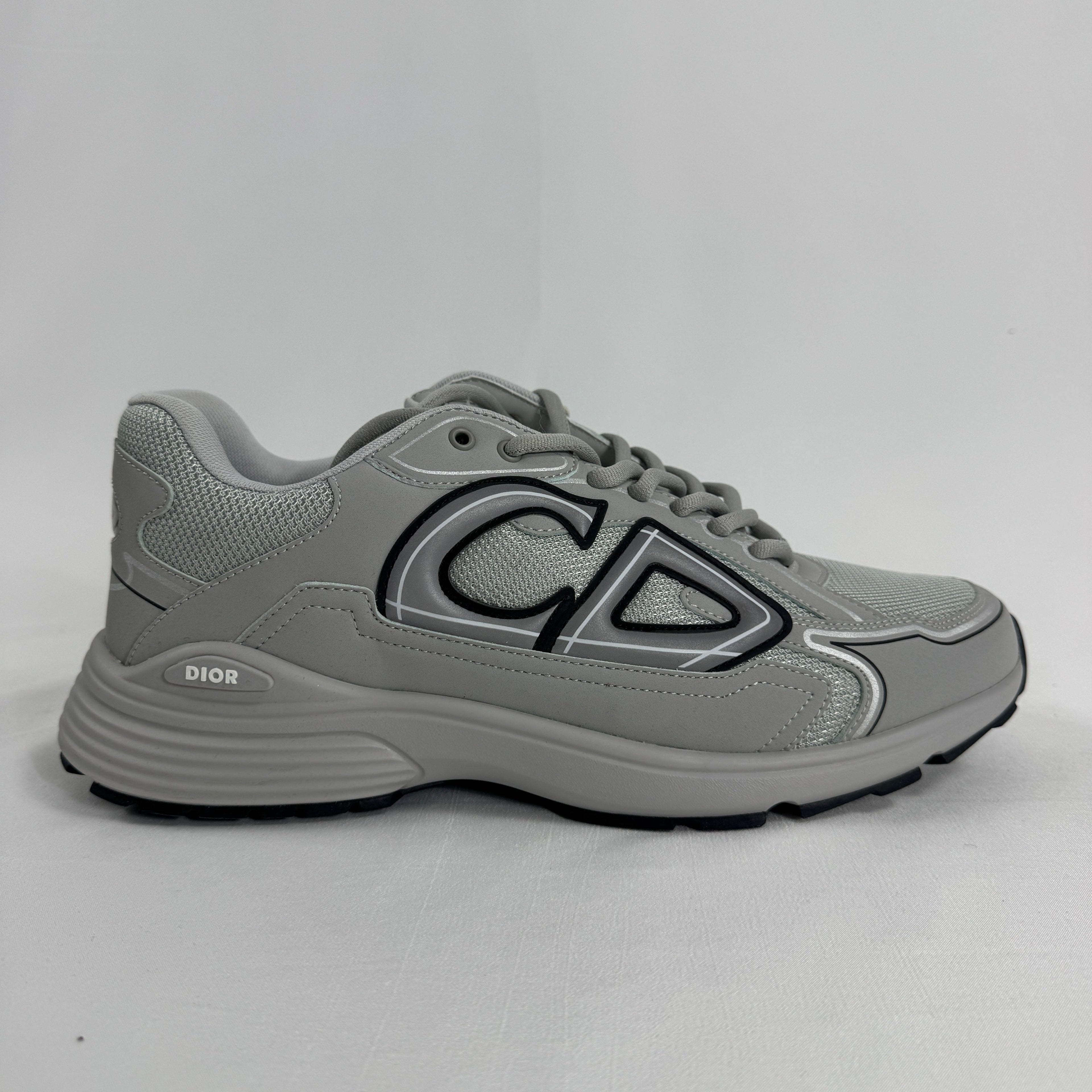 The Dior B30 Grey is a luxury sneaker featuring a technical mesh and microfiber upper in grey tones, with reflective