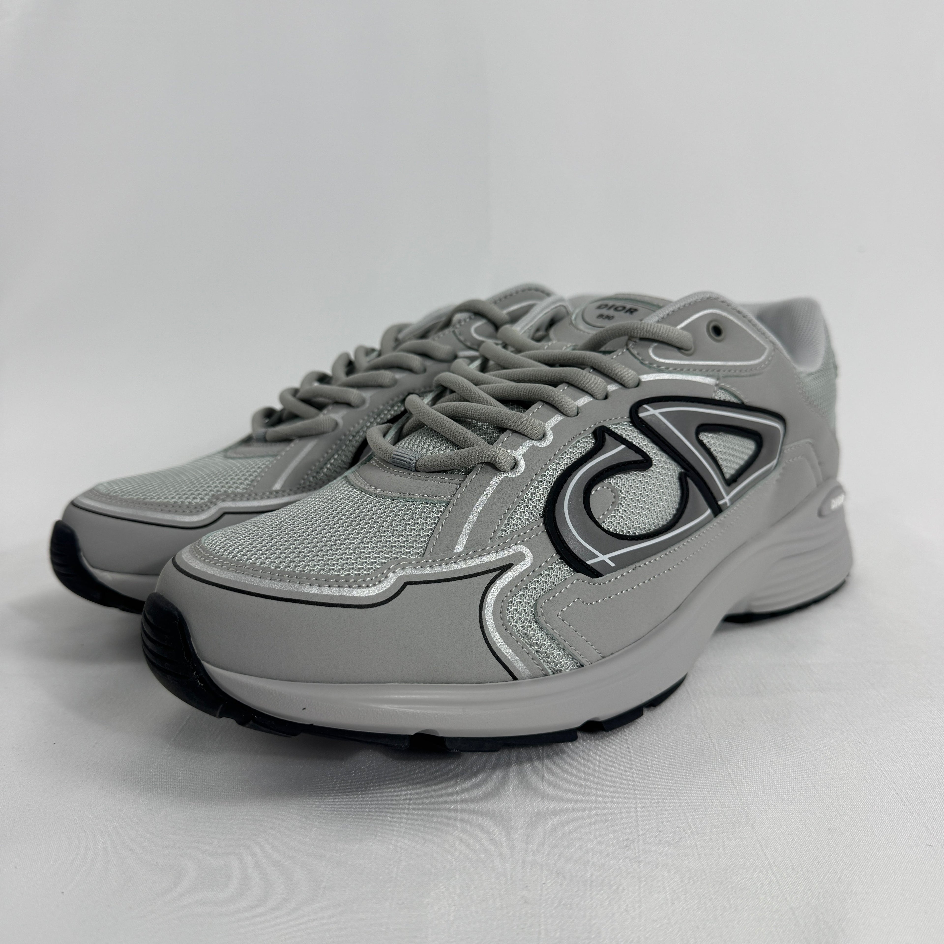 The Dior B30 Grey is a luxury sneaker featuring a technical mesh and microfiber upper in grey tones, with reflective