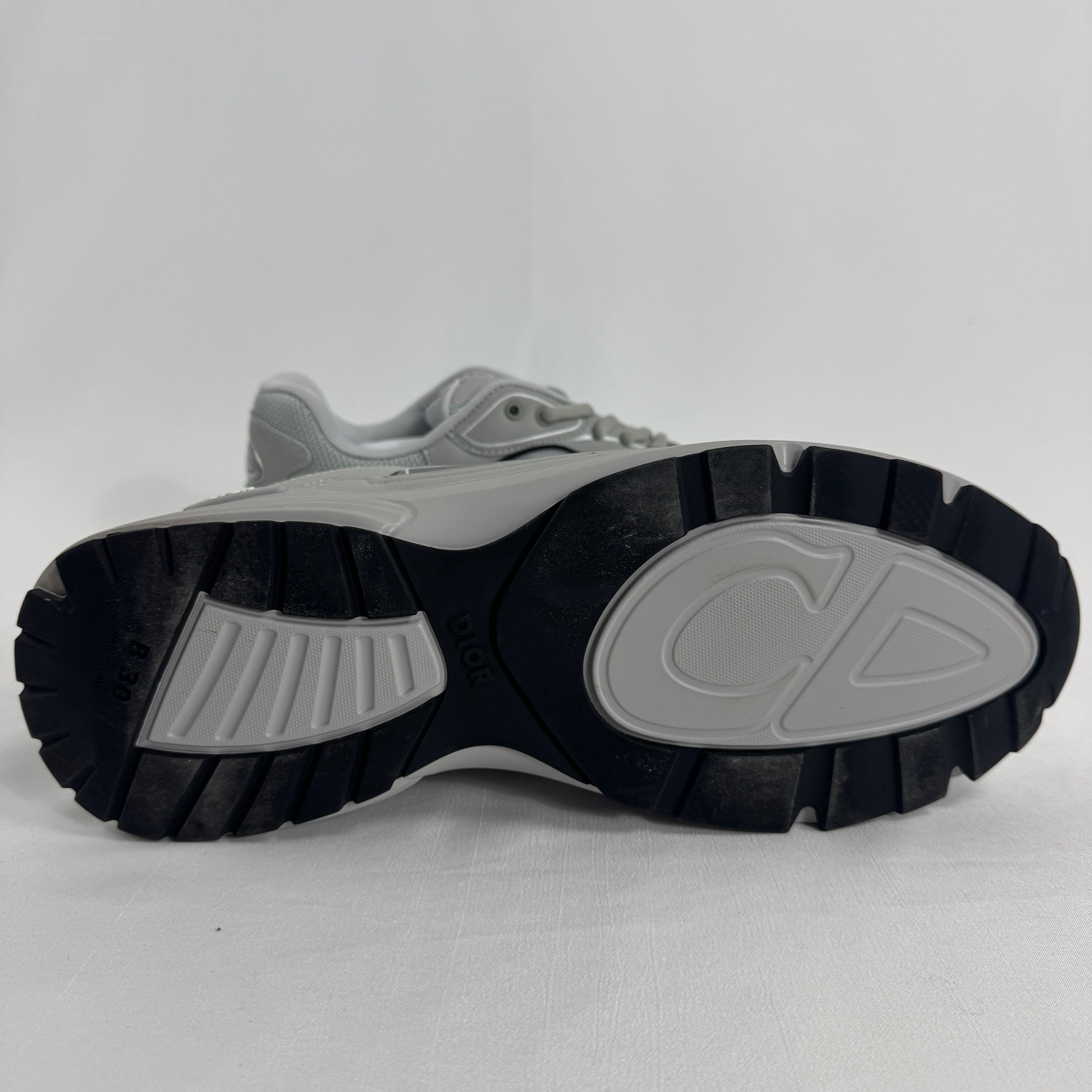 The Dior B30 Grey is a luxury sneaker featuring a technical mesh and microfiber upper in grey tones, with reflective