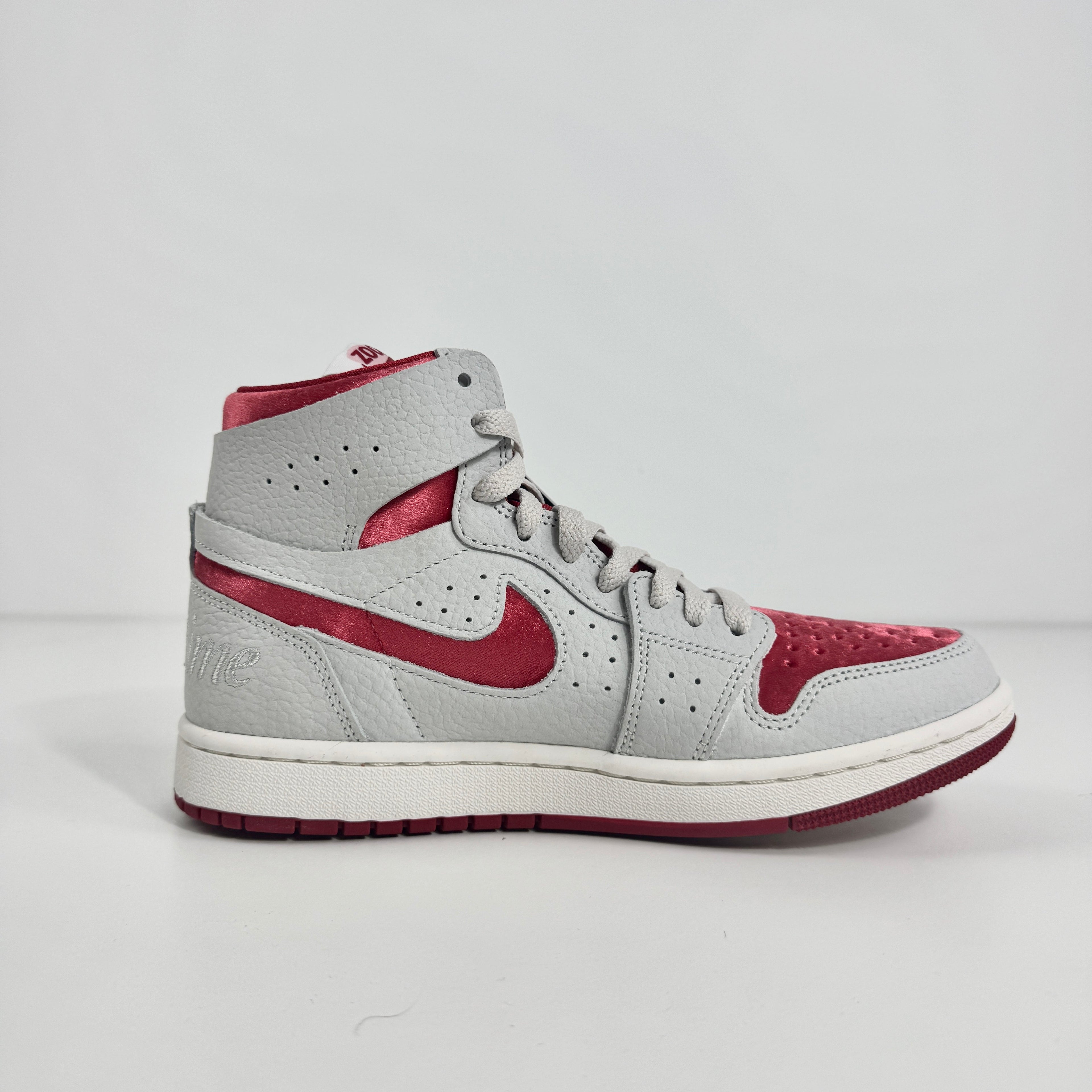 Jordan 1 Mid Zoom Grey/Red is a stylish mid-top sneaker featuring a grey upper with bold red accents for a striking look. It