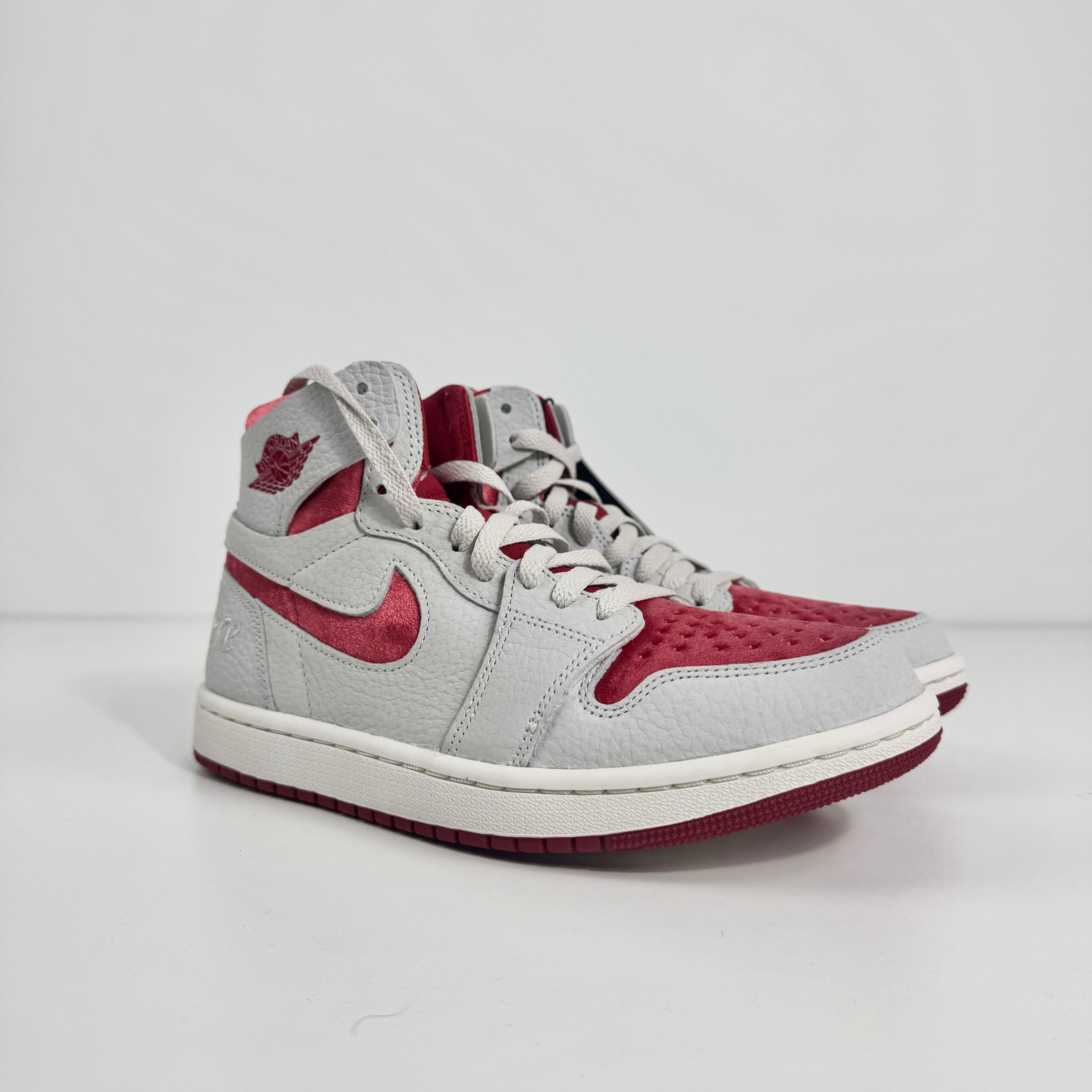 Jordan 1 Mid Zoom Grey/Red is a stylish mid-top sneaker featuring a grey upper with bold red accents for a striking look. It