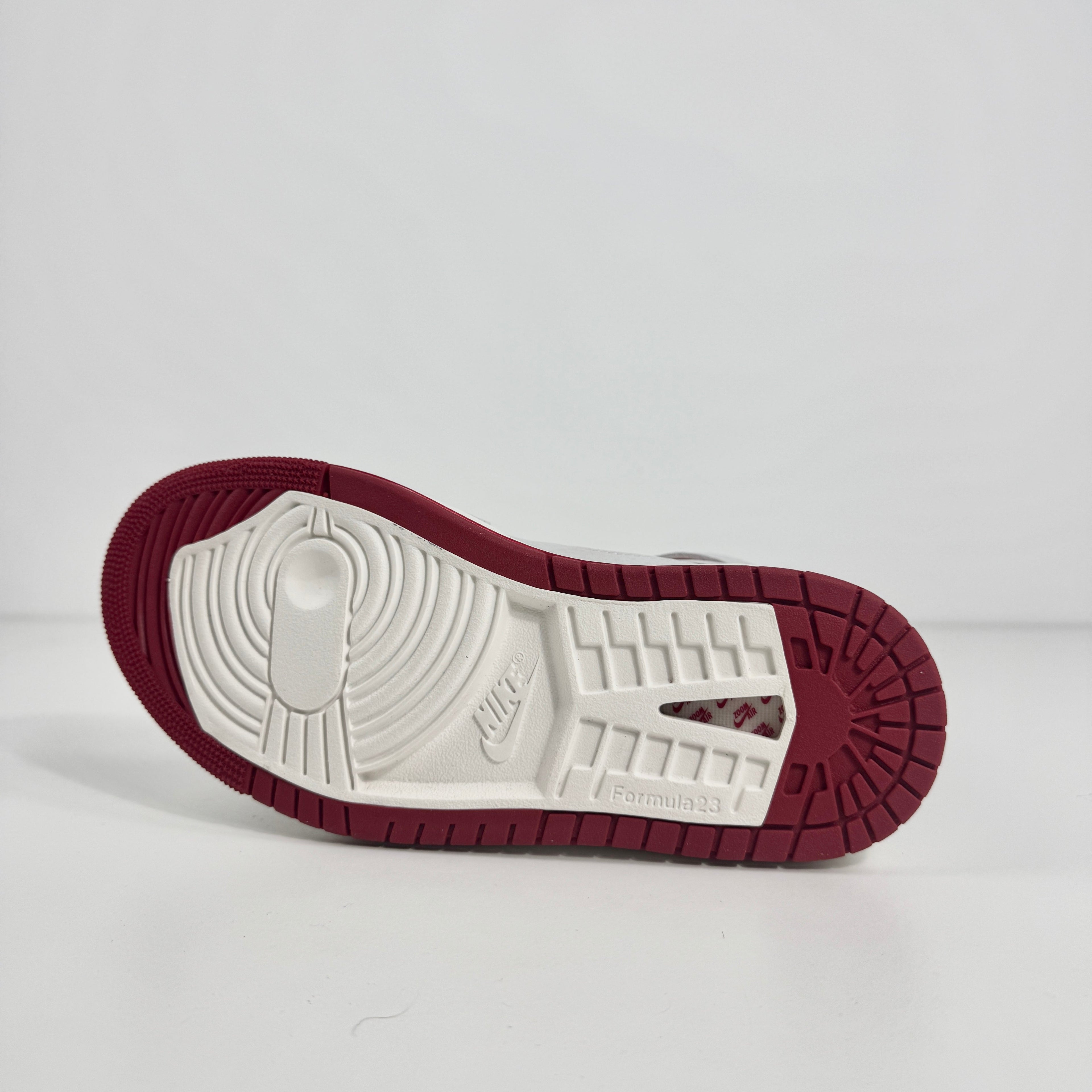 Jordan 1 Mid Zoom Grey/Red is a stylish mid-top sneaker featuring a grey upper with bold red accents for a striking look. It