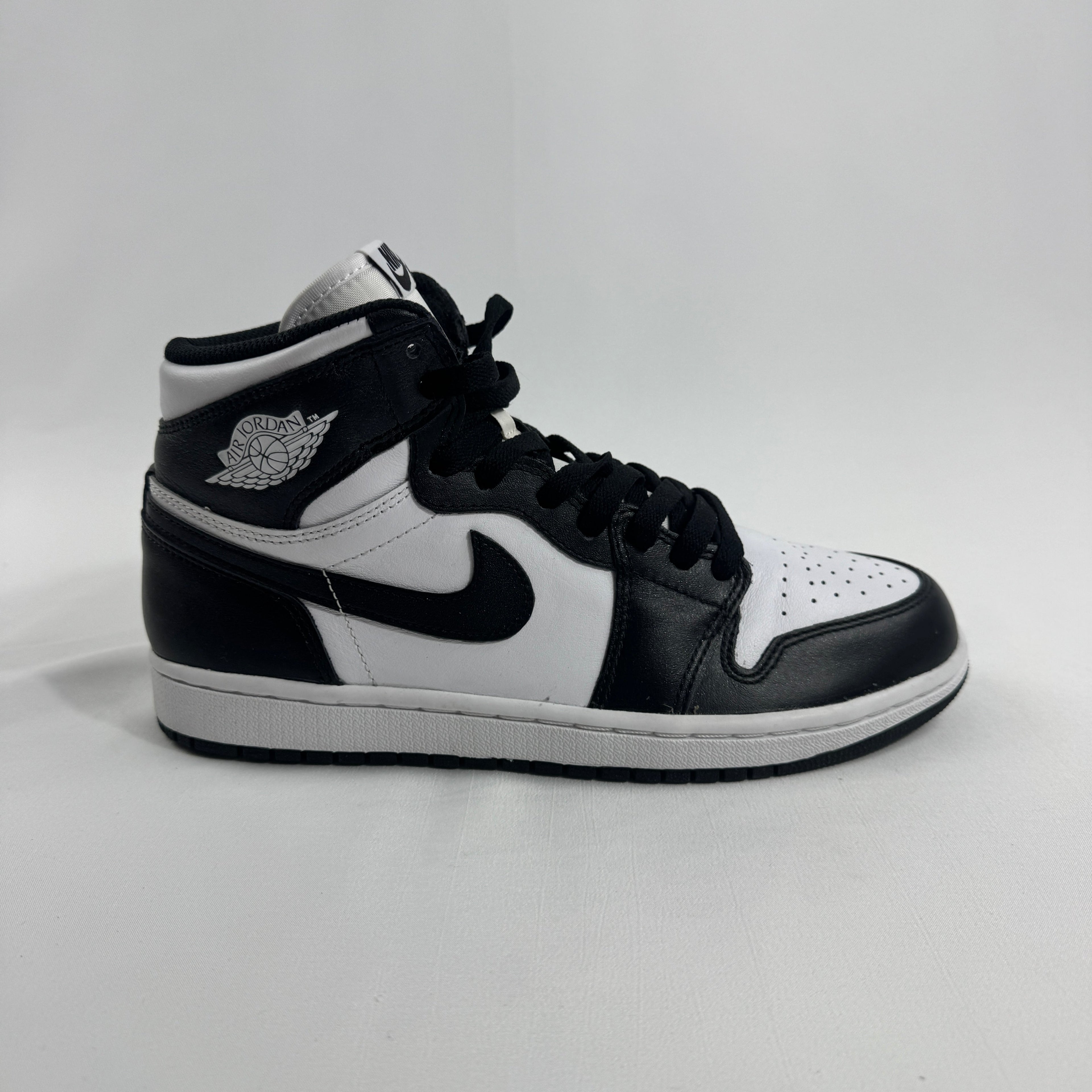 A black and white Nike high-top trainer with white laces and the Air Jordan wing logo on the collar, shown on a white background.