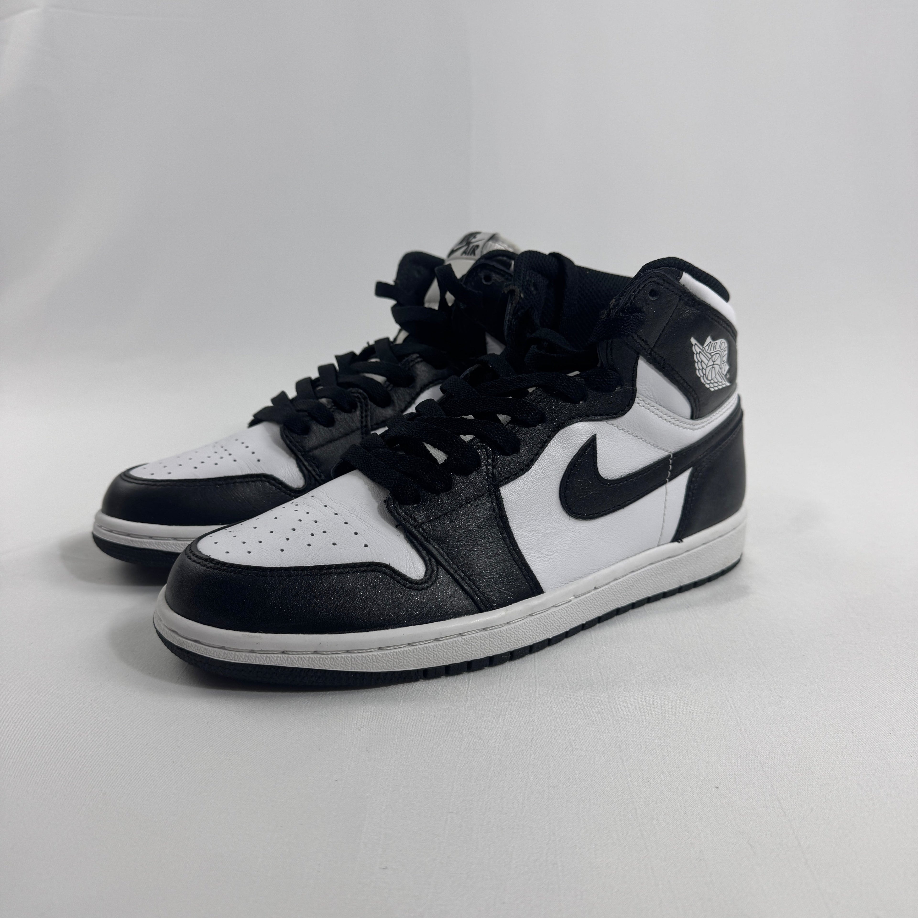 Nike Jordan 1 trainers in black and white with black laces, displayed against a plain white background.