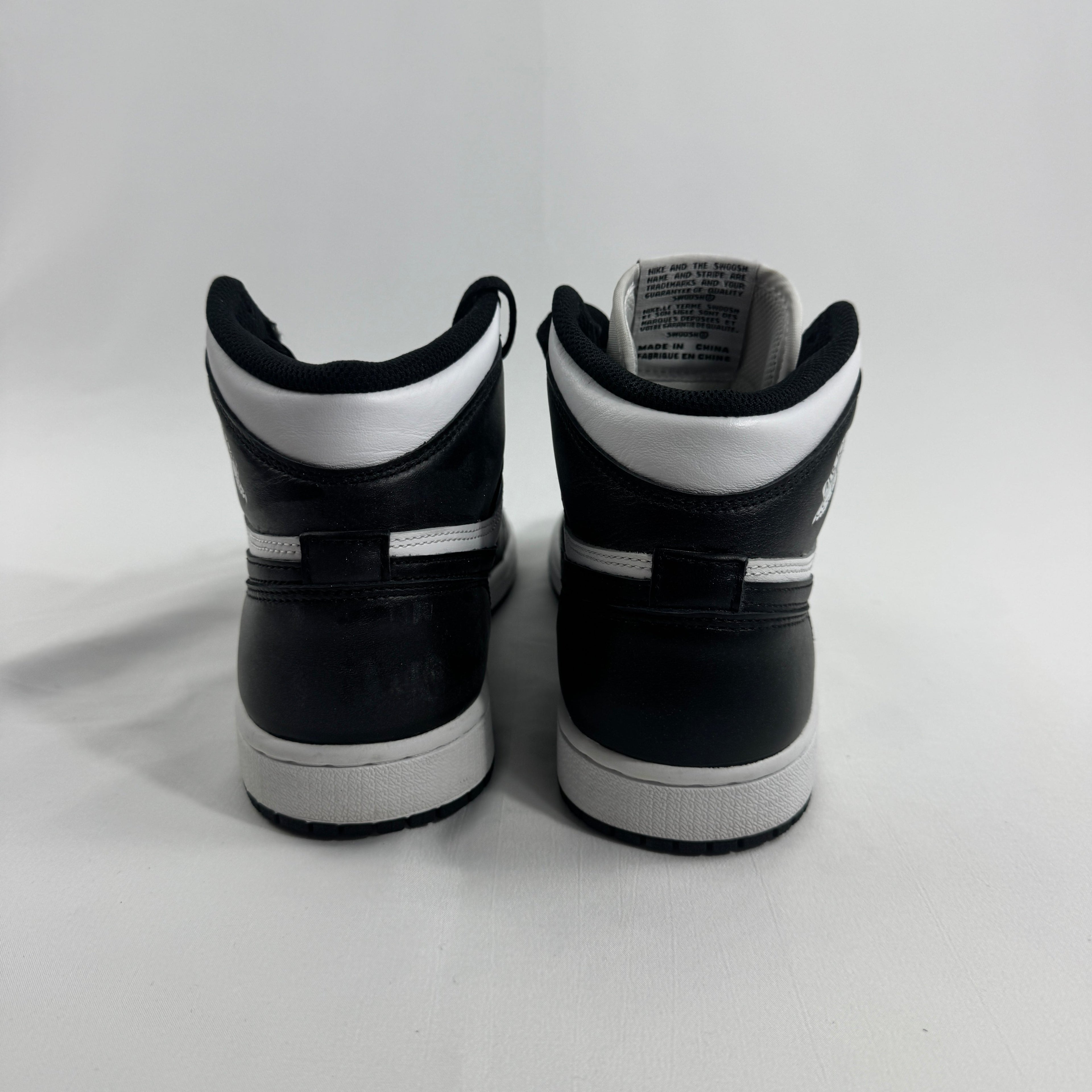 Two black and white Nike high-top trainers are placed side by side, facing away on a plain white background.