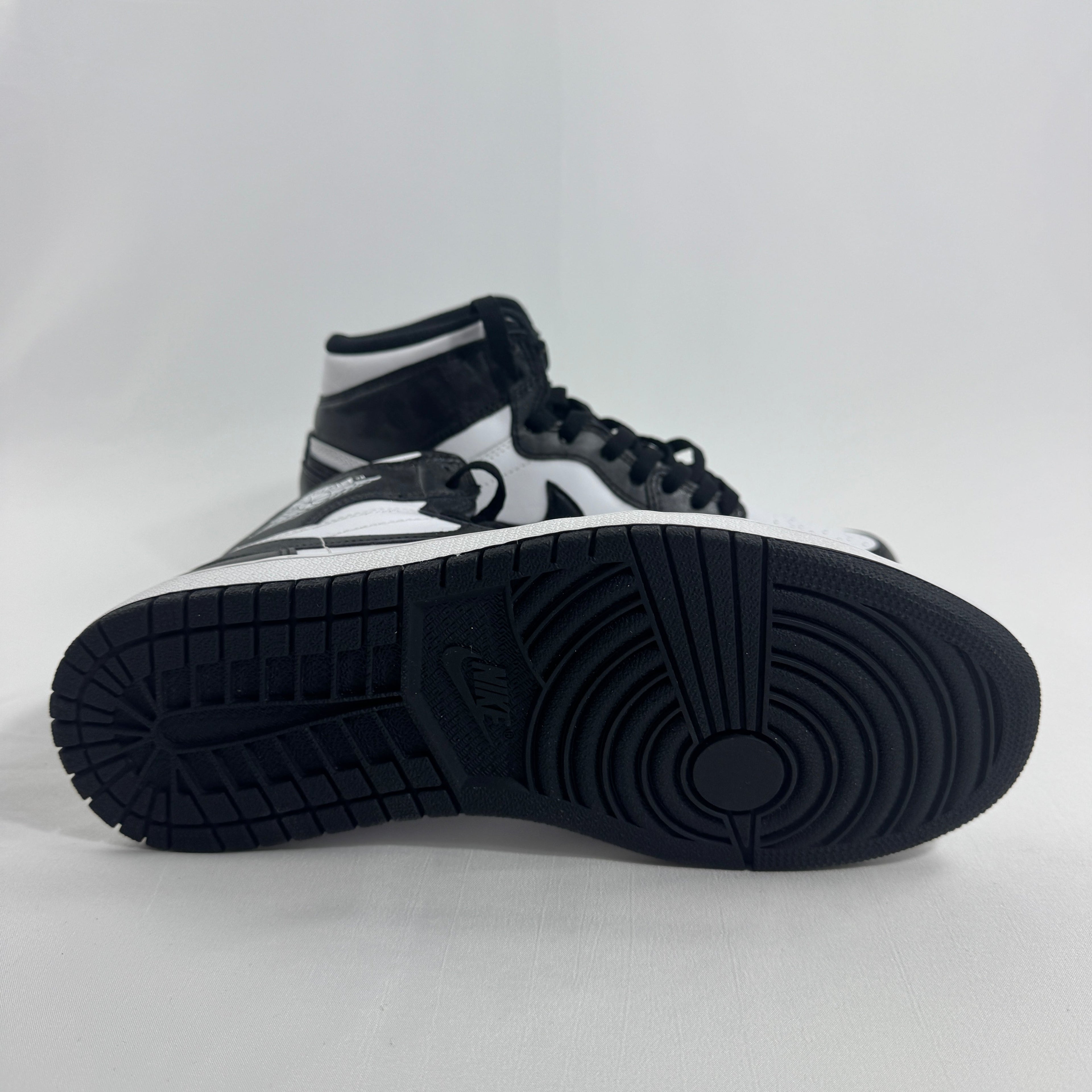 A NIKE black and white high-top trainer is shown side-on, emphasising the sole texture and side profile on a plain white background.