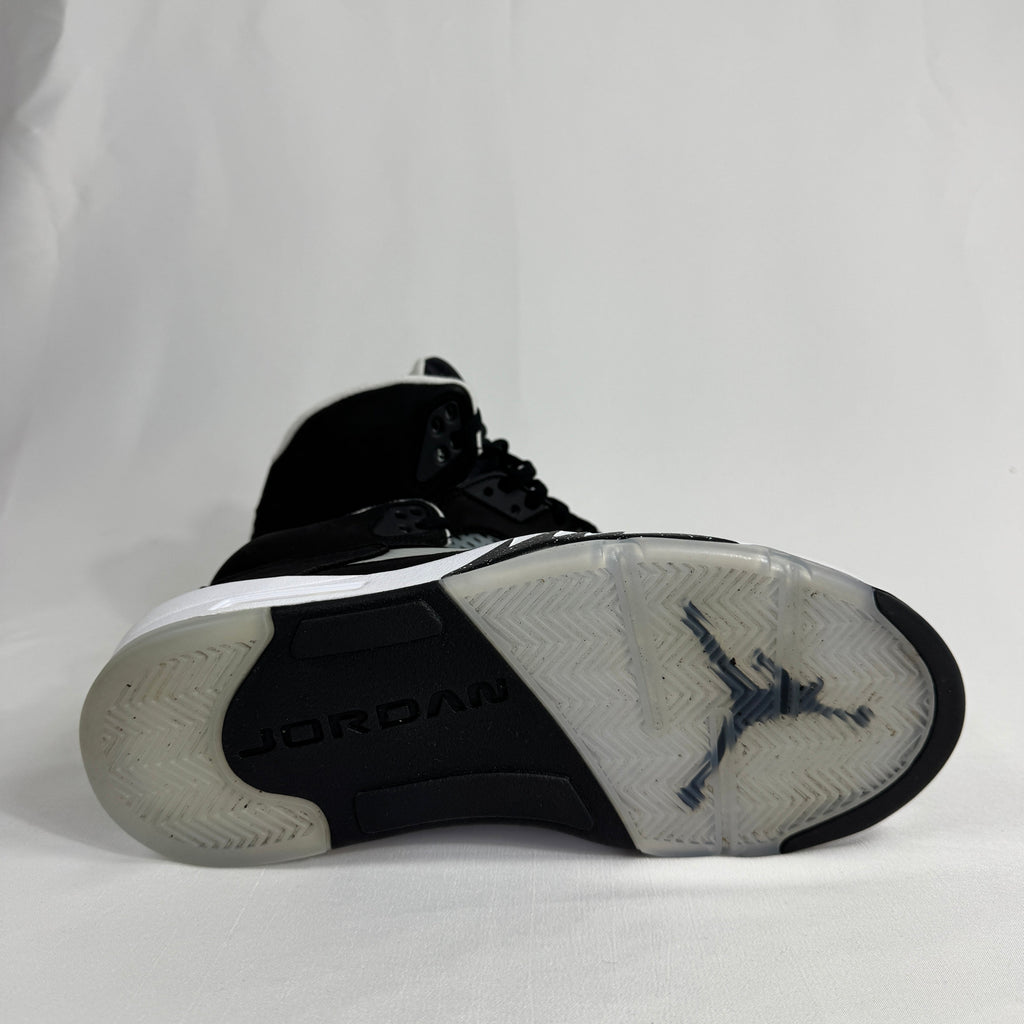 The Jordan 5 Retro Oreo is a classic basketball-inspired sneaker featuring a black nubuck upper, signature reflective
